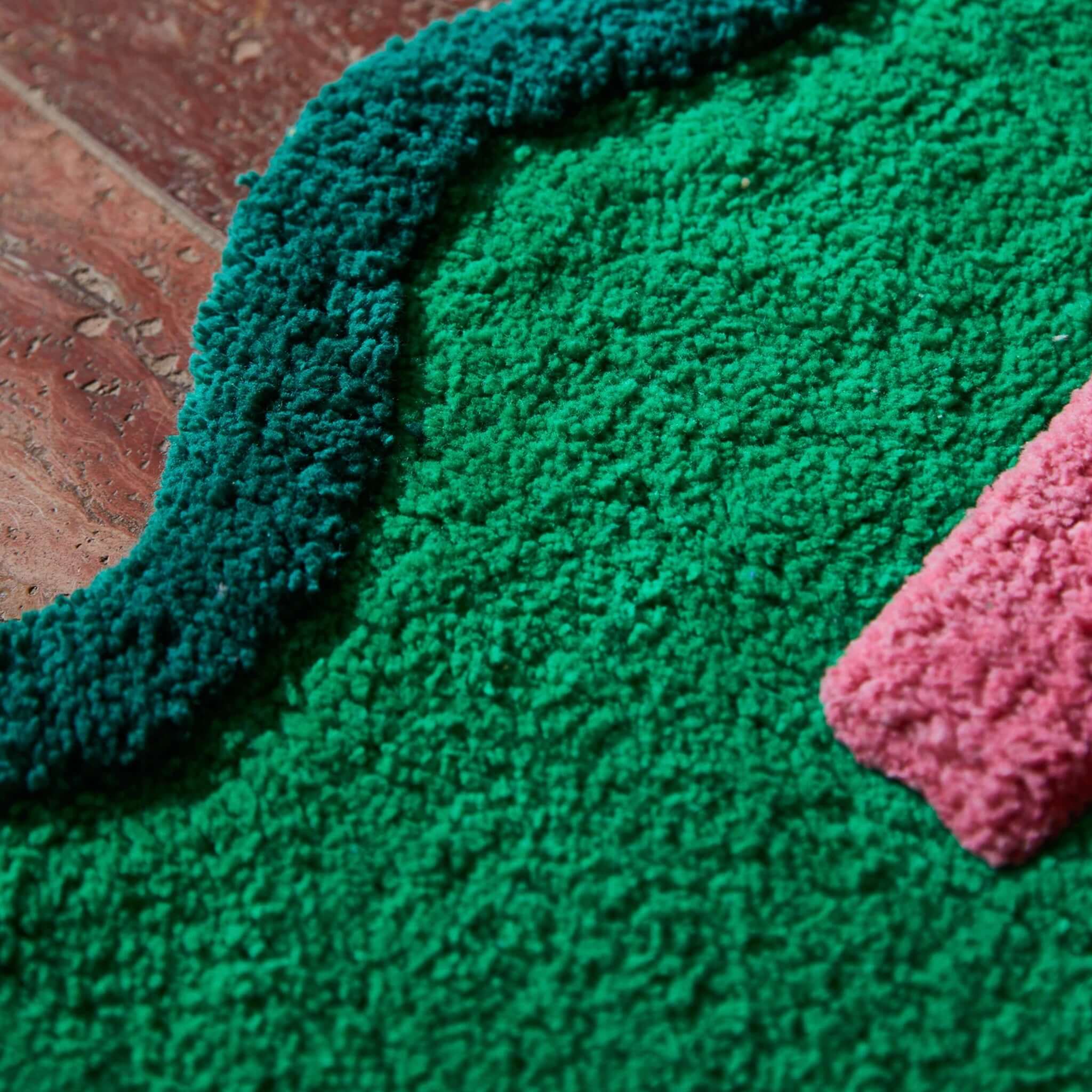 Sage x Clare Amalie Nudie Bath Mat - Spring Green close-up, showcasing vibrant green and pink colors, hand-tufted detail.