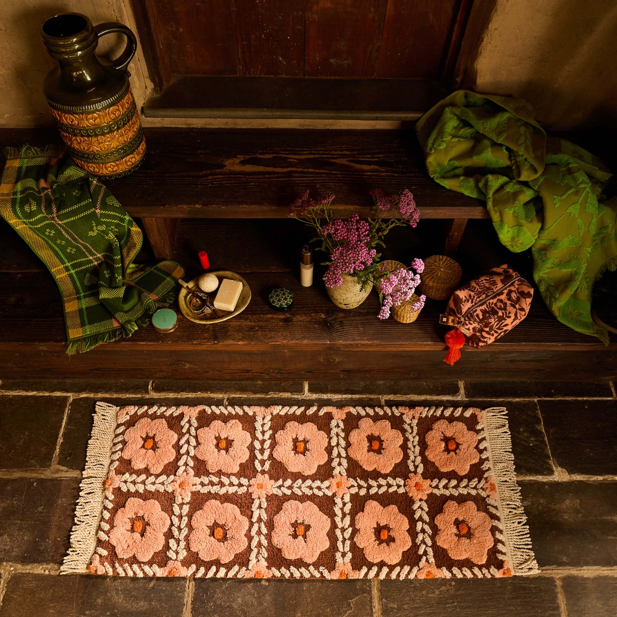 Sage x Clare Billy Bath Runner with peach flowers on chocolate ground, knotted fringe, and surrounded by decorative items.