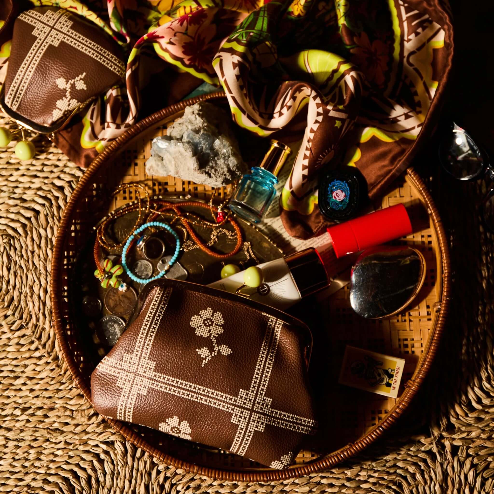 Sage x Clare Bonny Large Purse - Umber with accessories in a woven basket.