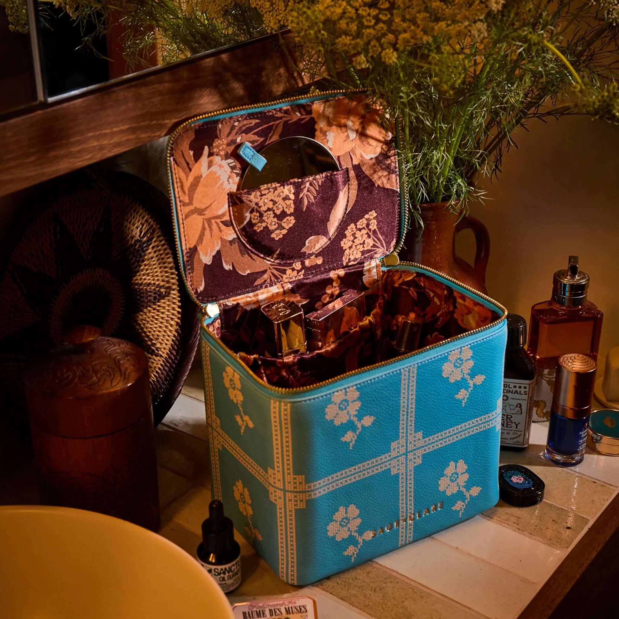 Sage x Clare Bonny Medium Vanity Case - Turquoise open with beauty products inside on a stylish vanity.
