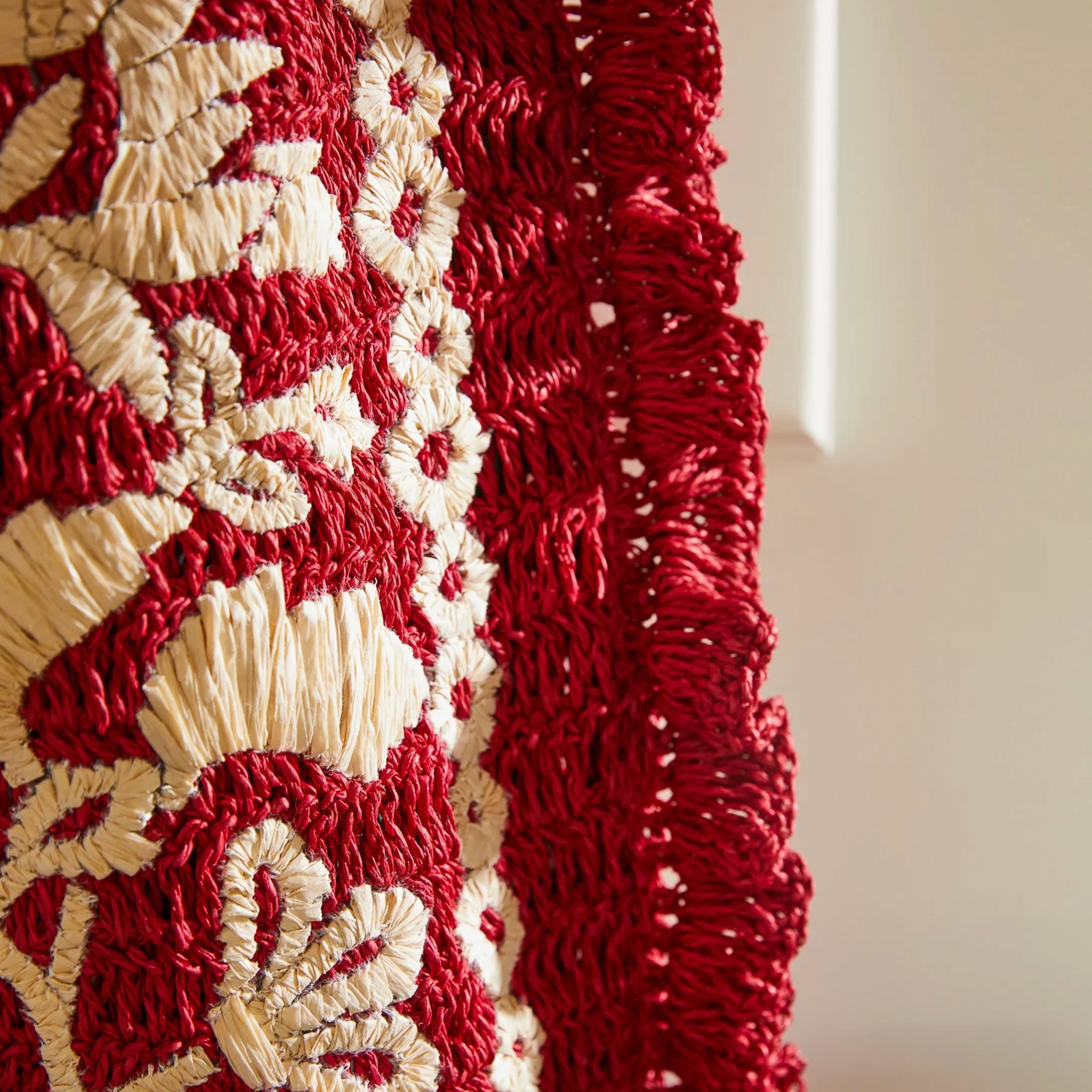 Close-up of a textured red and beige fabric with floral patterns.