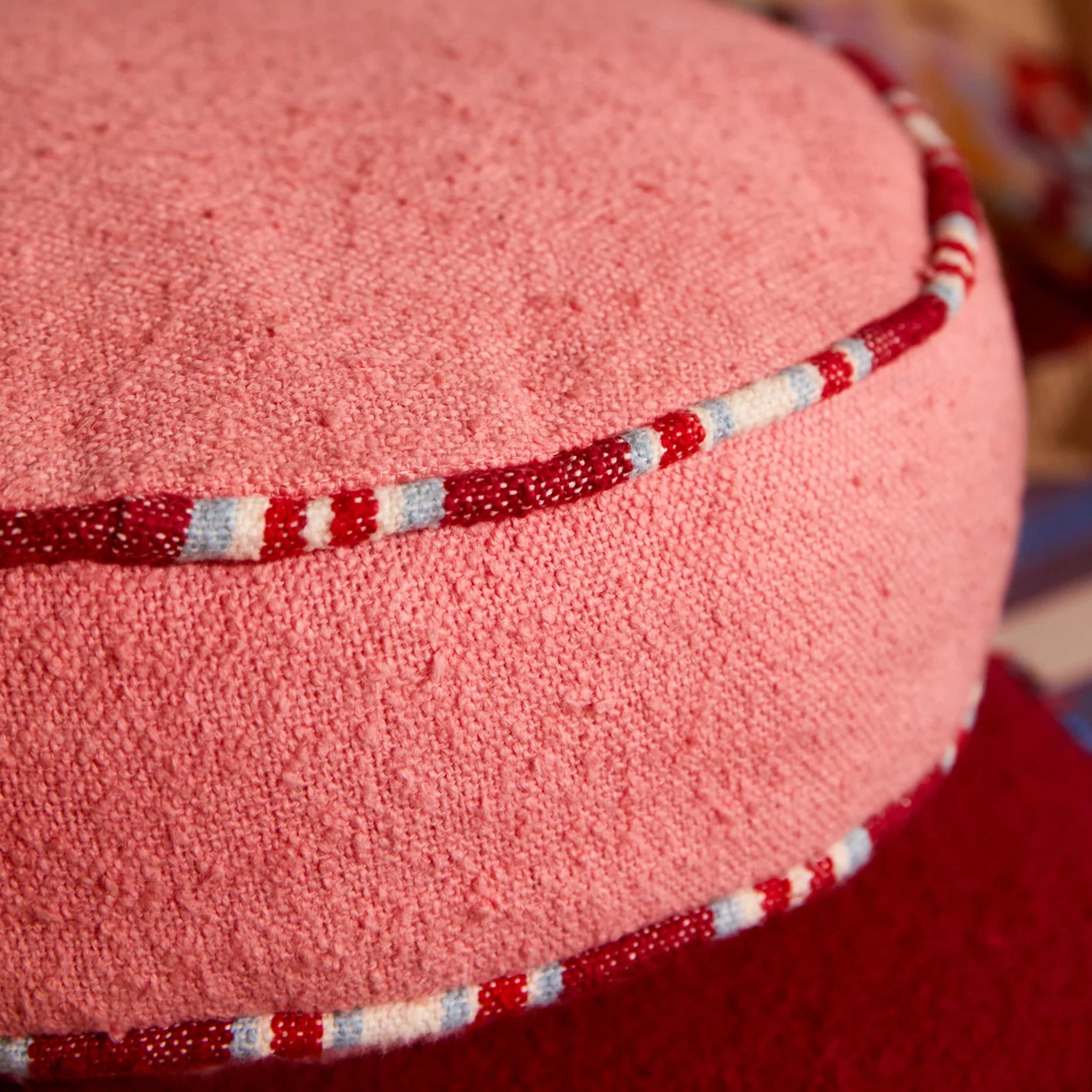 Close-up of a pink cushion with a red and white striped trim