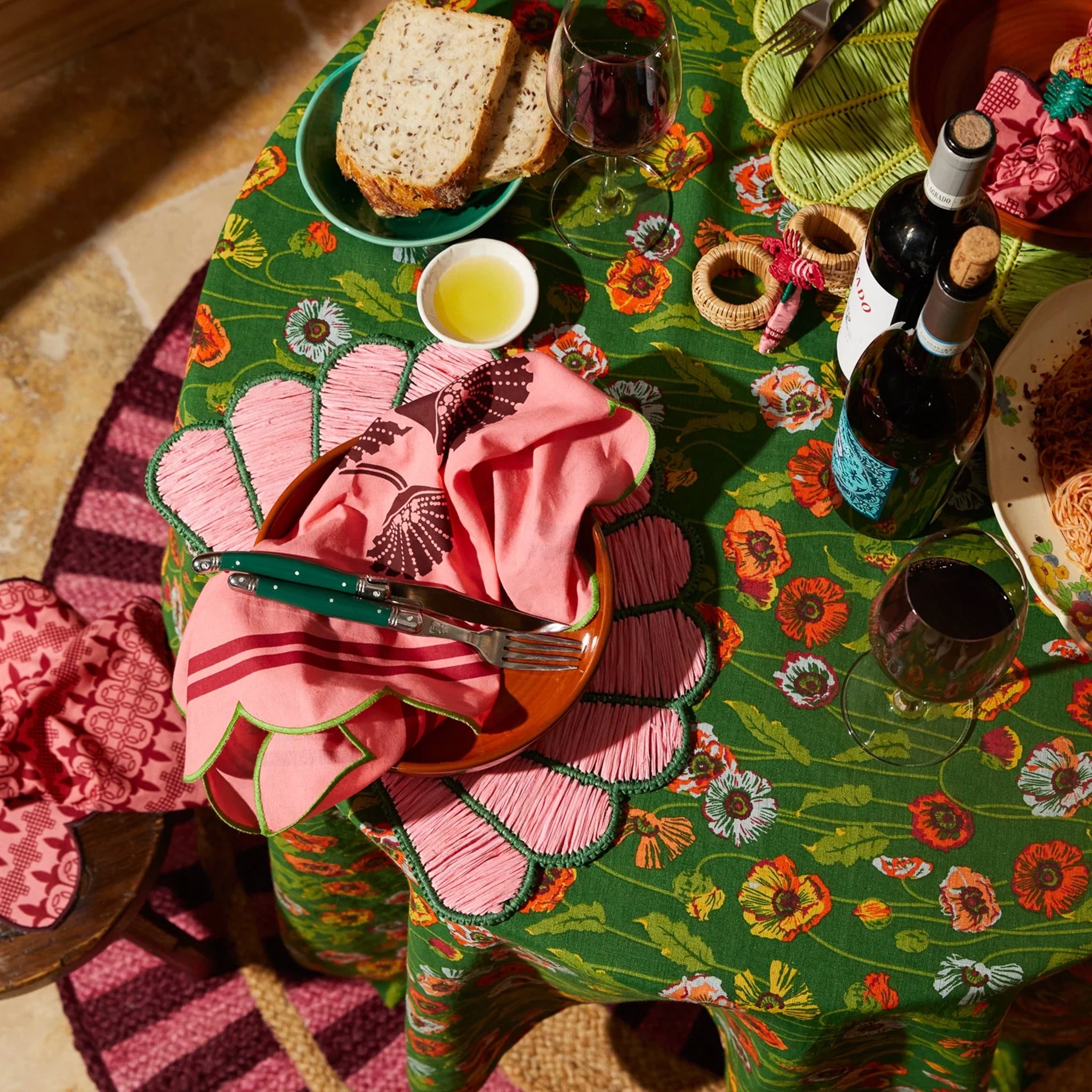 Decorative table setting with floral tablecloth, pink napkin, and food items.