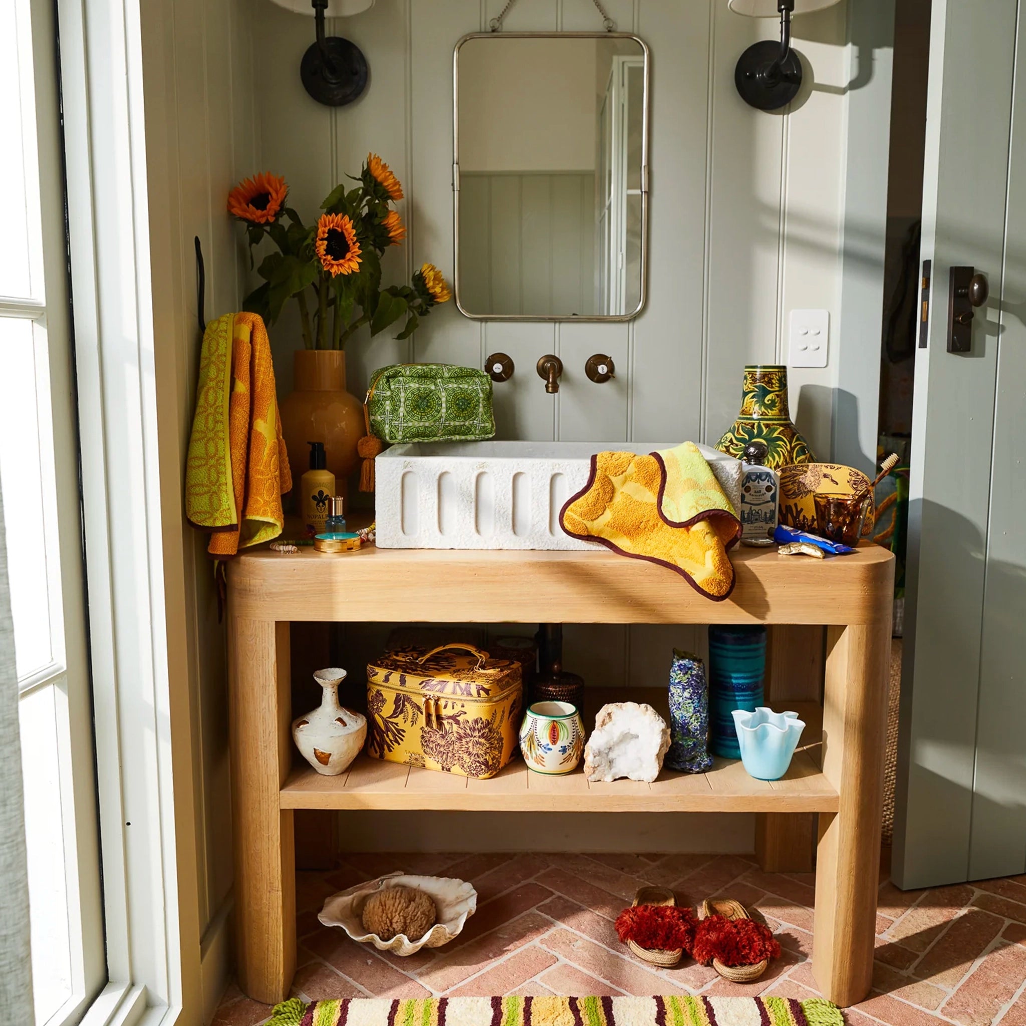 Bathroom with wooden vanity, mirror, and various decorative items.