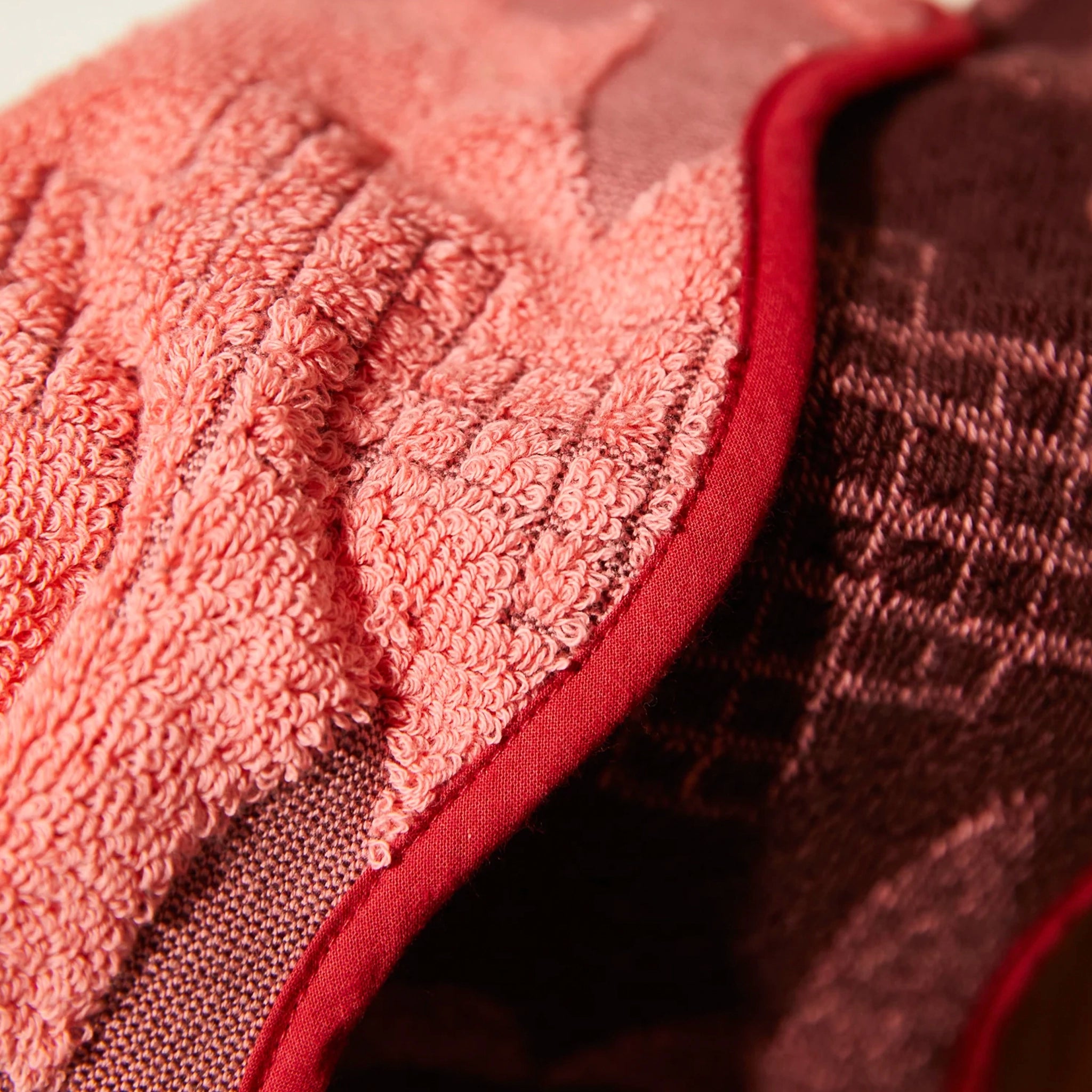 Close-up of a textured pink wash cloth with a dark brown background