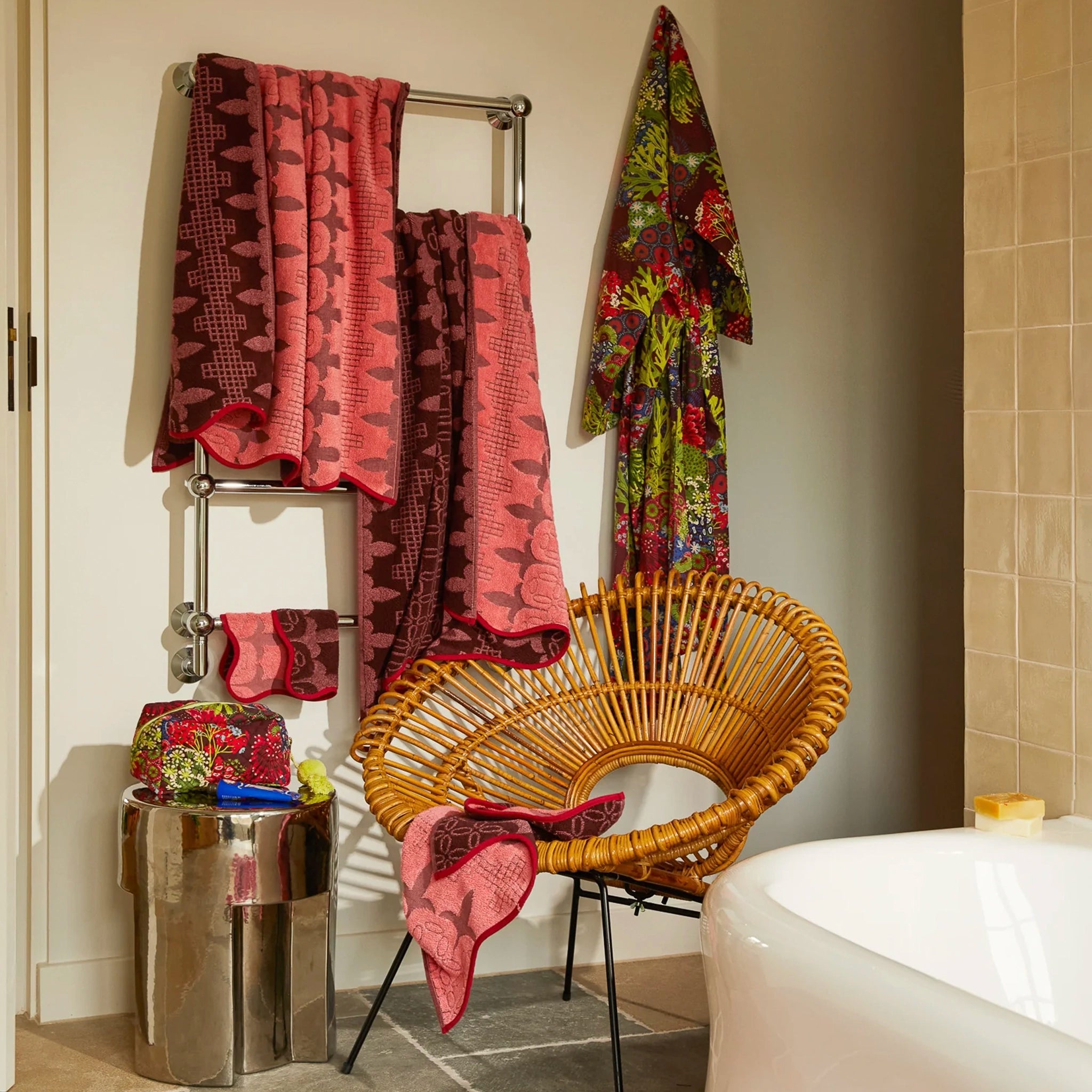 Bathroom scene with towels on a rack, a wicker chair, and a bathtub.
