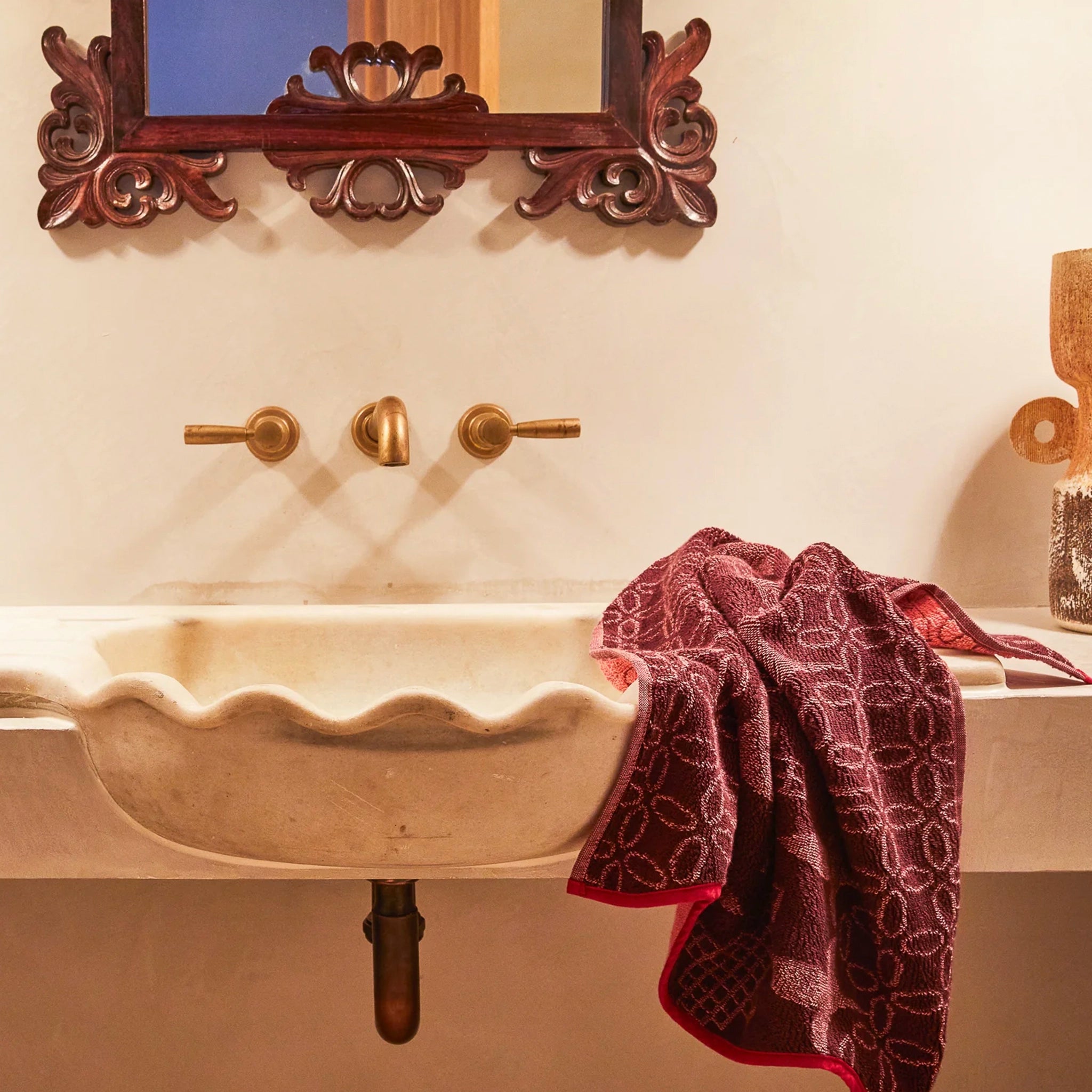 Bathroom sink with decorative mirror, faucet, and towel.