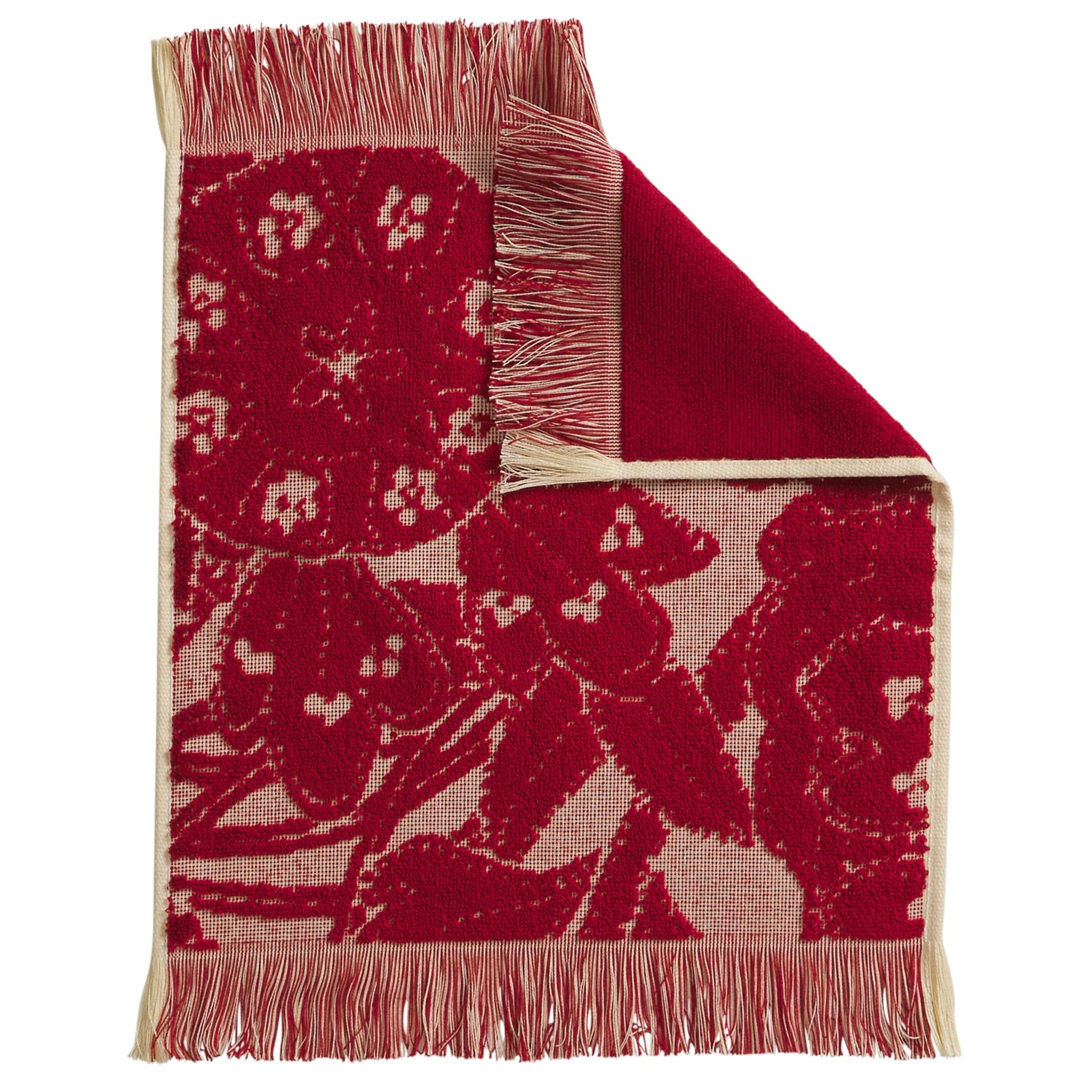 Red floral patterned face washer with beige fringe on a white background