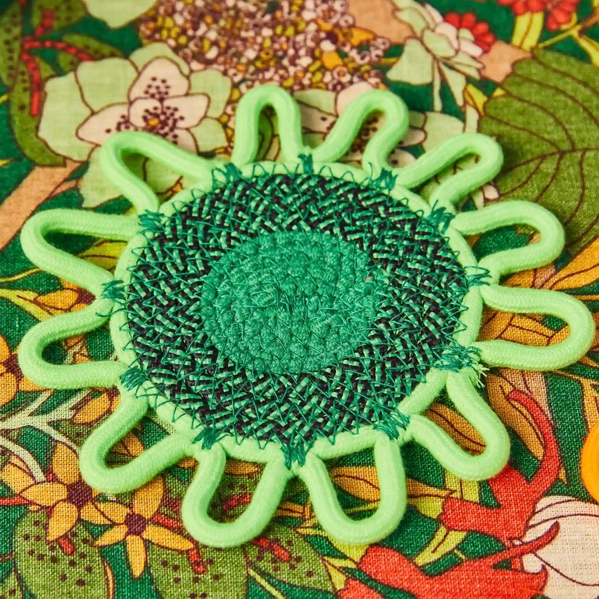 Green woven coaster on a colorful floral fabric background