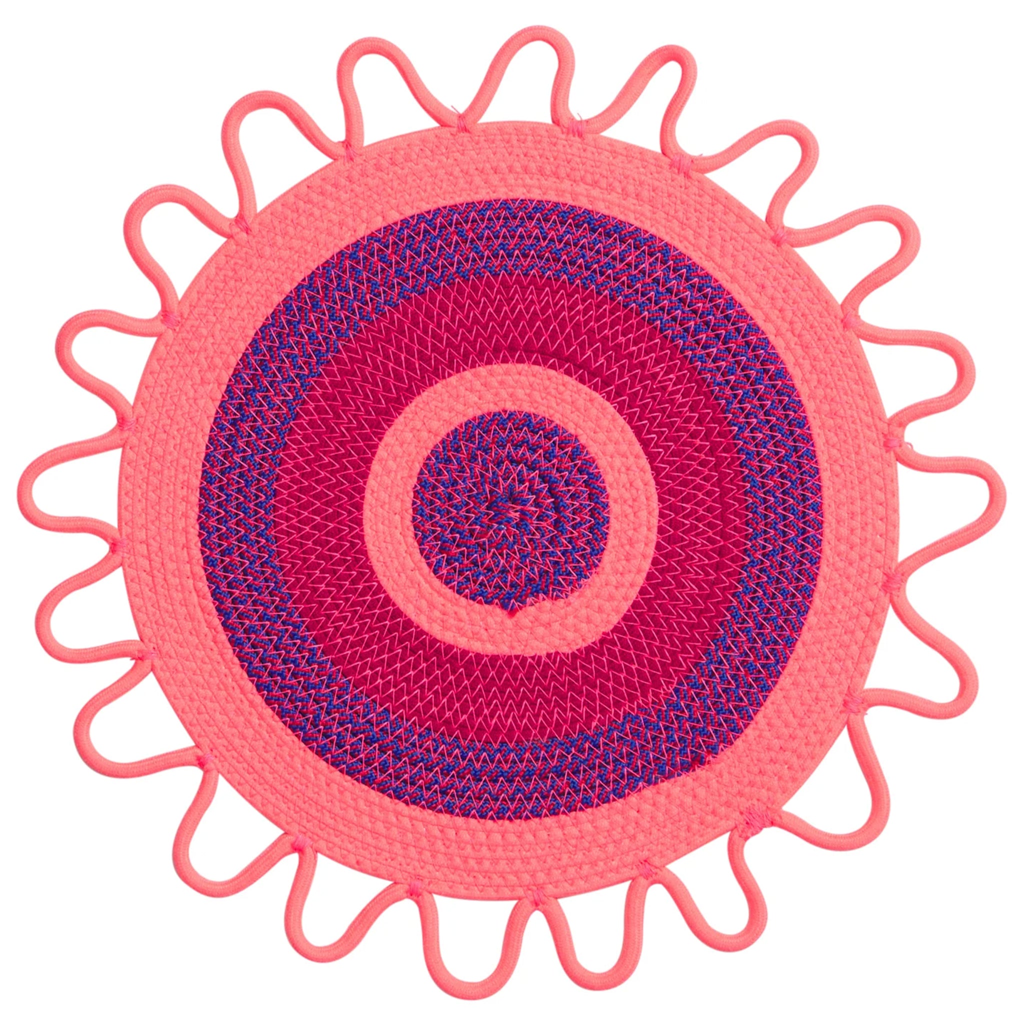 Round pink and purple placemat with decorative edge on a white background