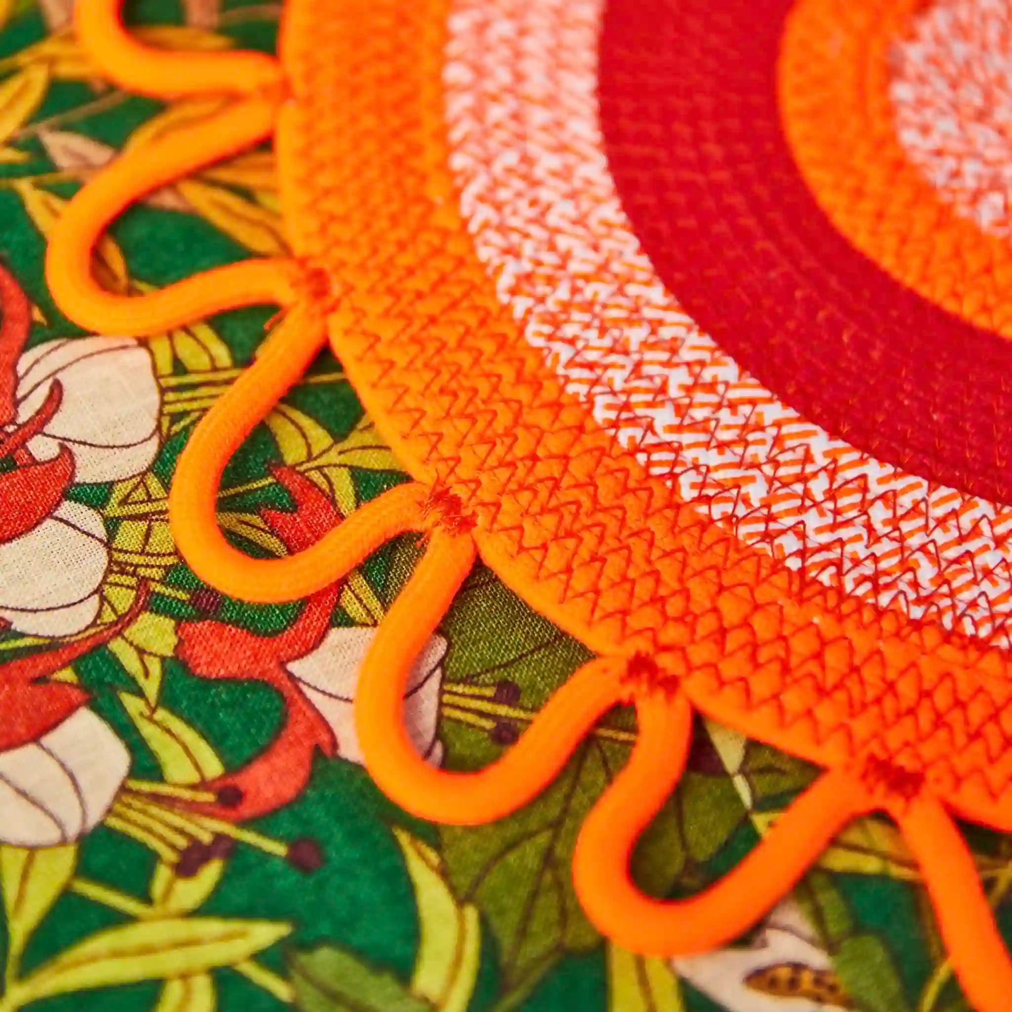 Close-up of orange textured placemat with floral pattern in the background