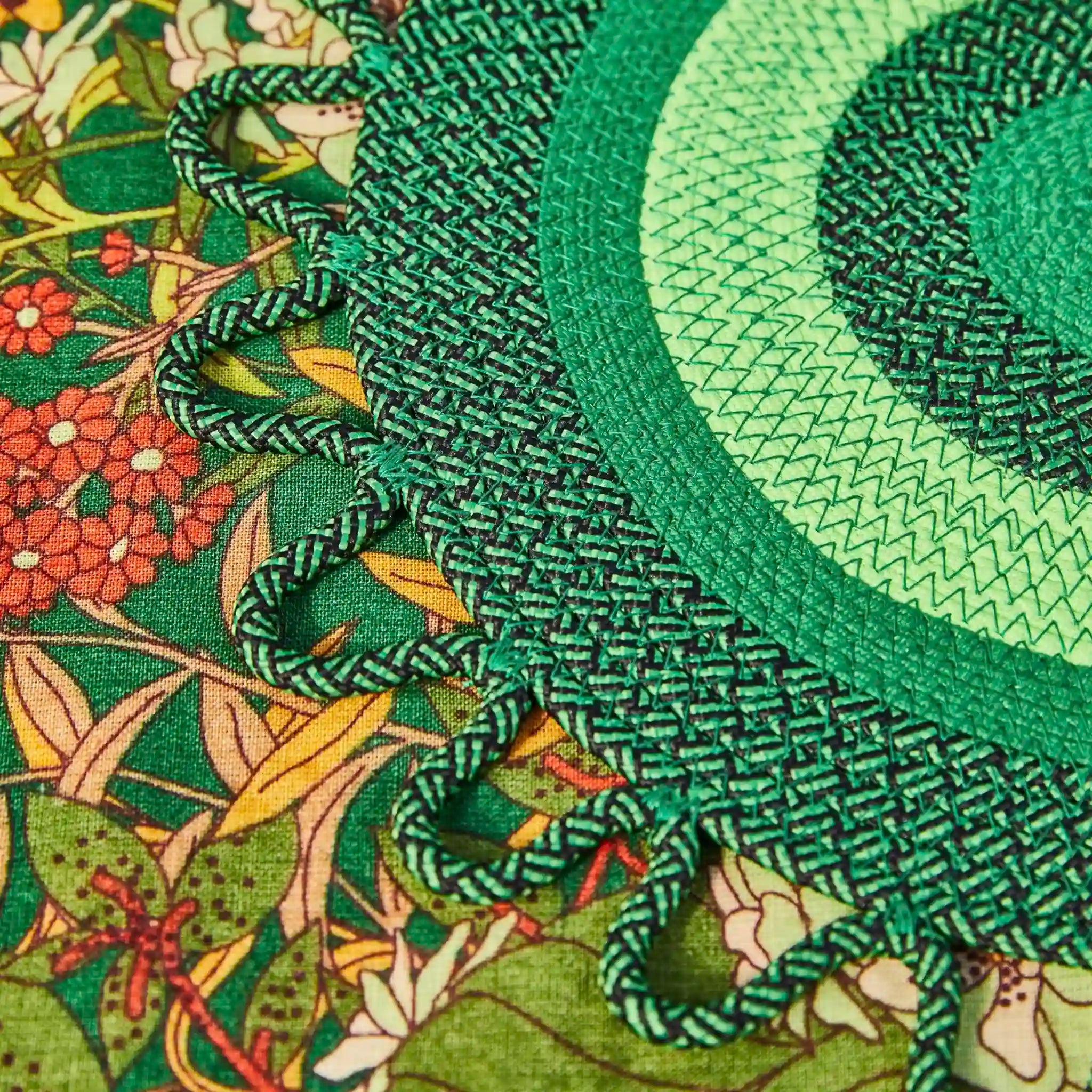 Close-up of green braided placemat on a floral-patterned fabric background