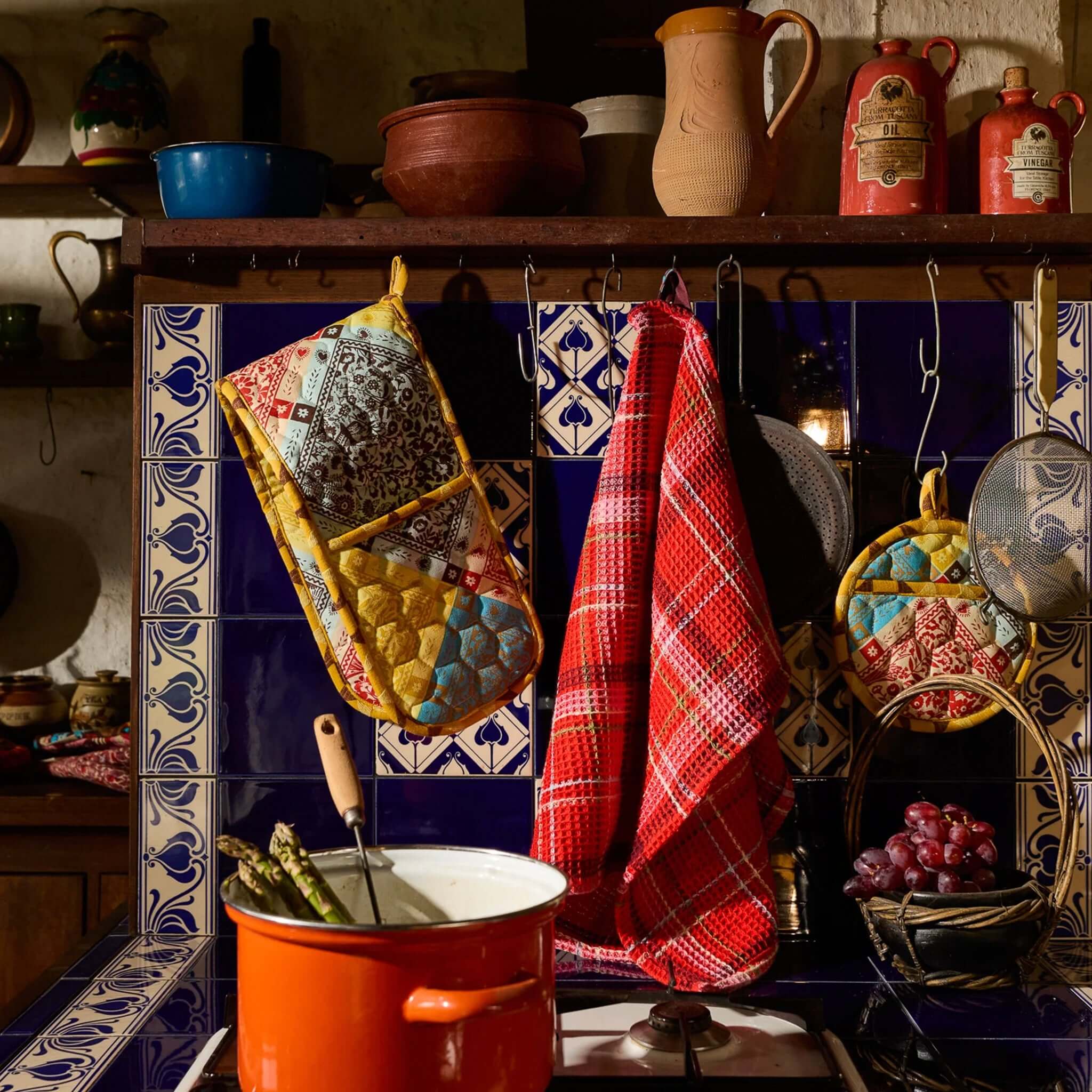 Sage x Clare Frances Organic Cotton Waffle Tea Towel - Poppy hanging in a rustic kitchen with colorful pots.