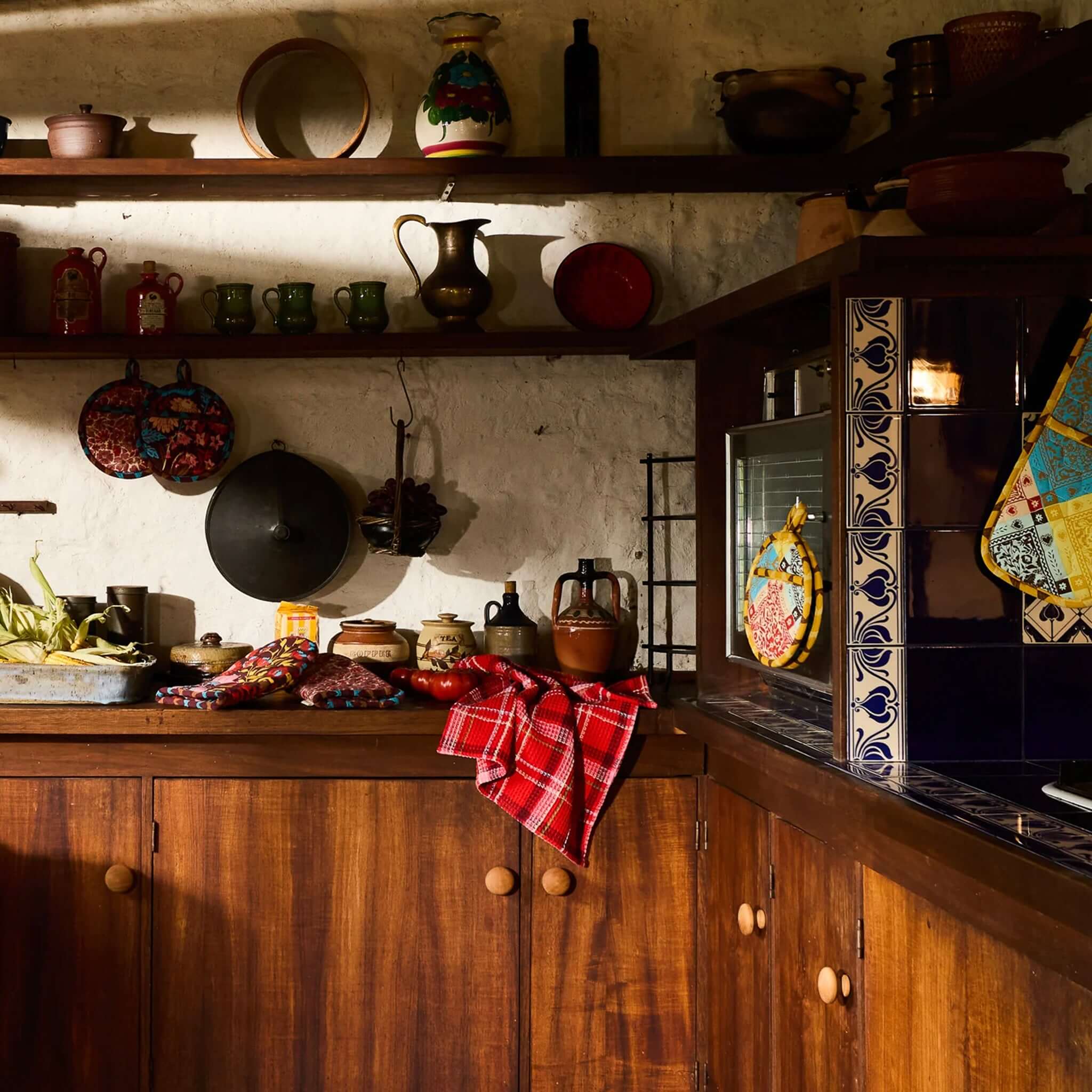 Sage x Clare Frances Organic Cotton Waffle Tea Towel - Poppy hanging in a rustic kitchen setting with wooden cabinets.
