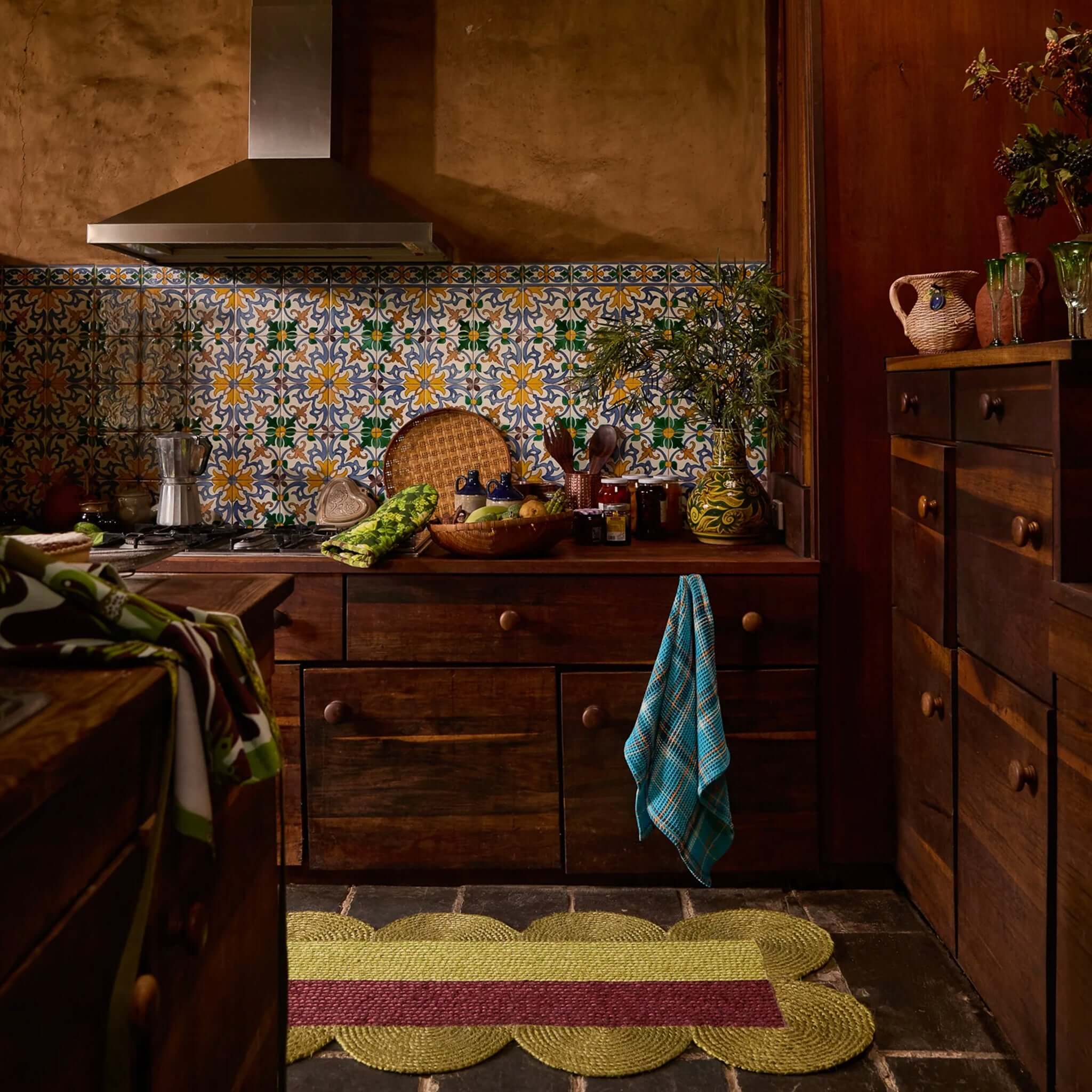 Sage x Clare Frances Organic Cotton Waffle Tea Towel - Turquoise hanging in a cozy kitchen with wooden cabinets and colorful tiles.