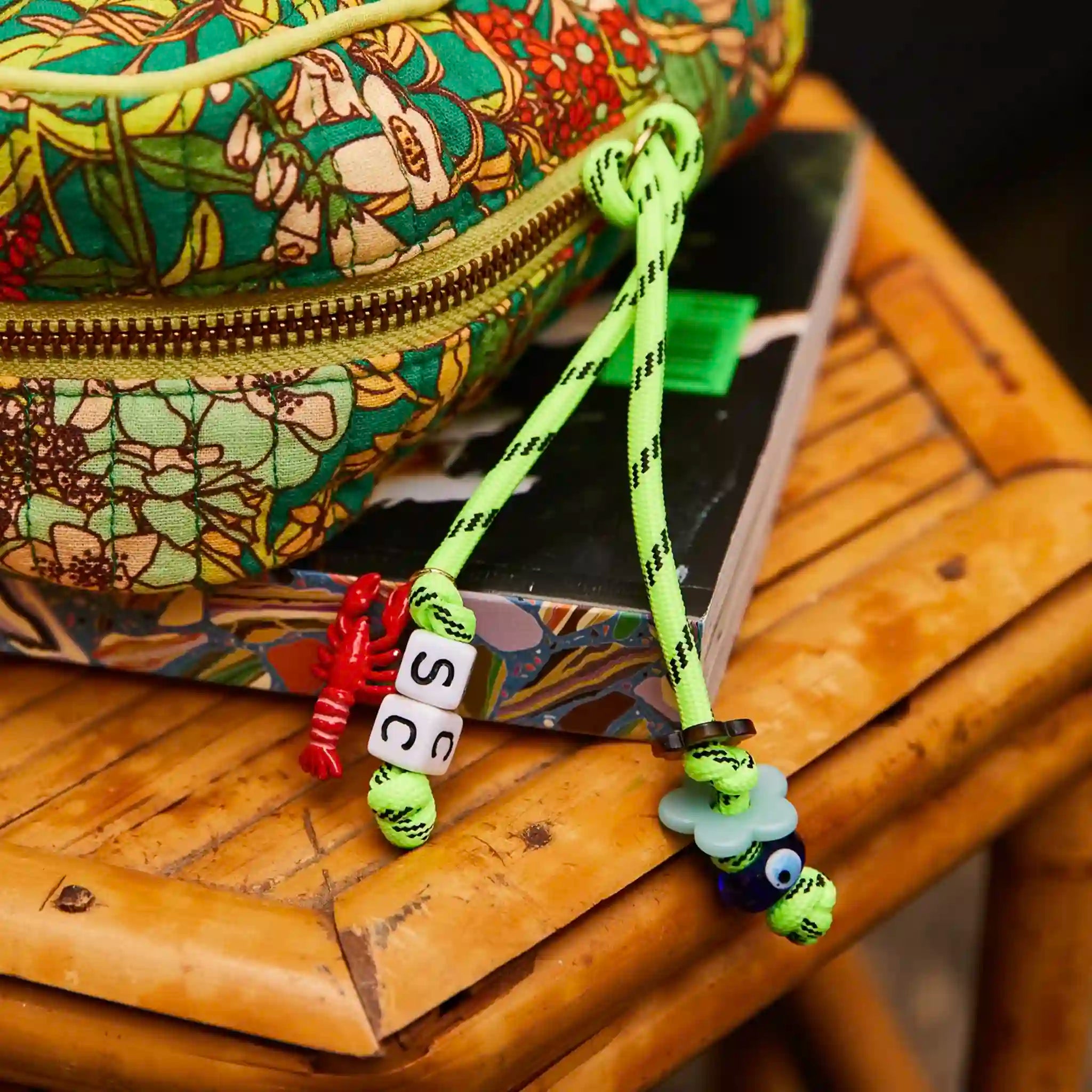 Colorful bag with a decorative strap featuring beads and charms on a wooden surface.