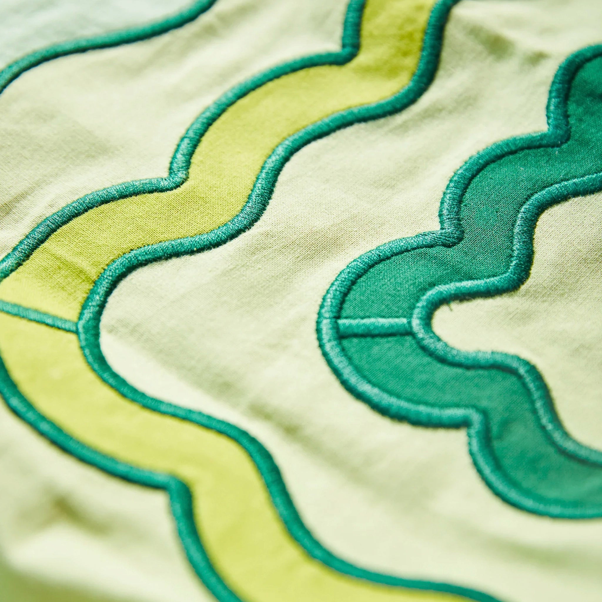 Close-up of green and yellow napkin with wavy patterns on a beige background
