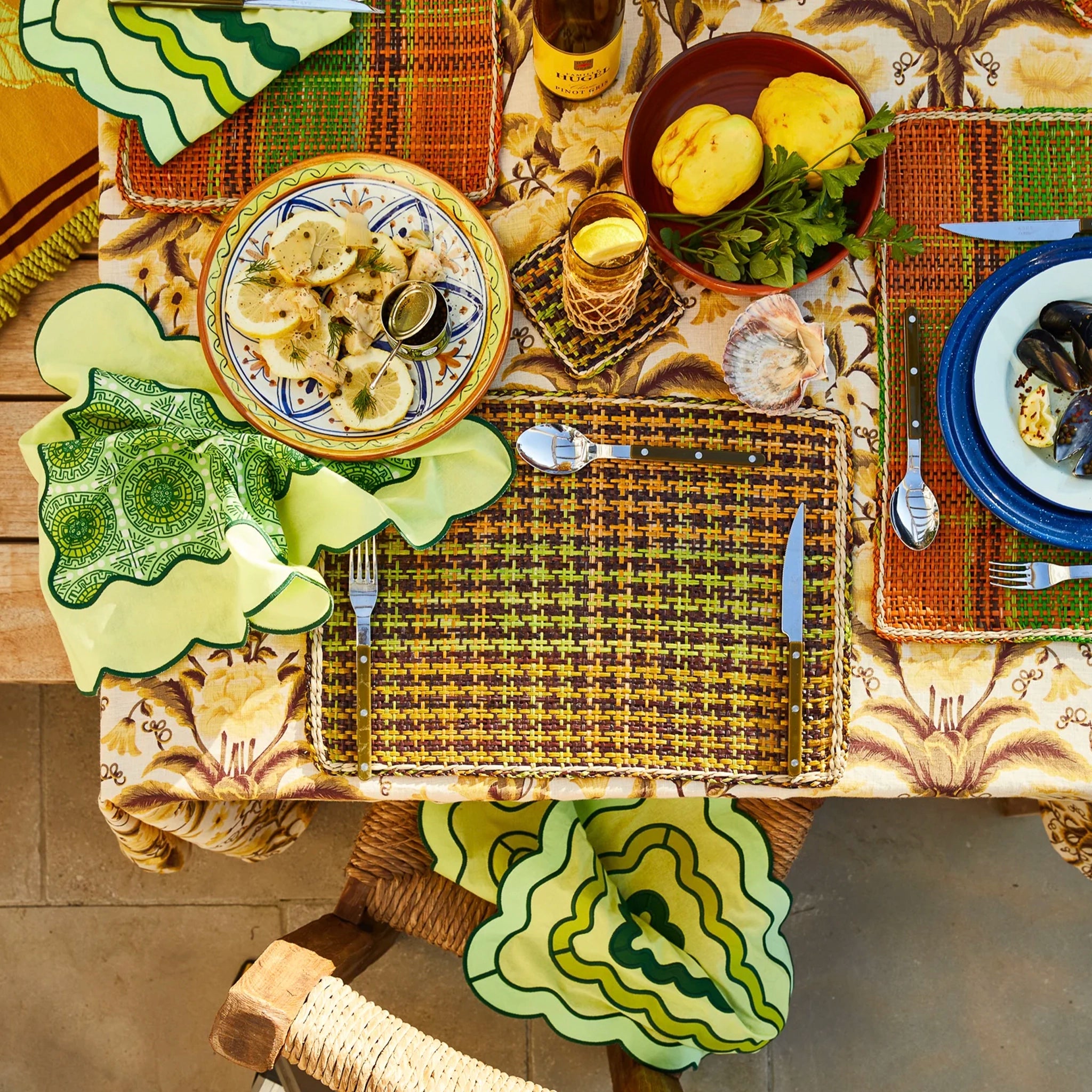 Dining table set with plates, cutlery, and food on a patterned napkin.