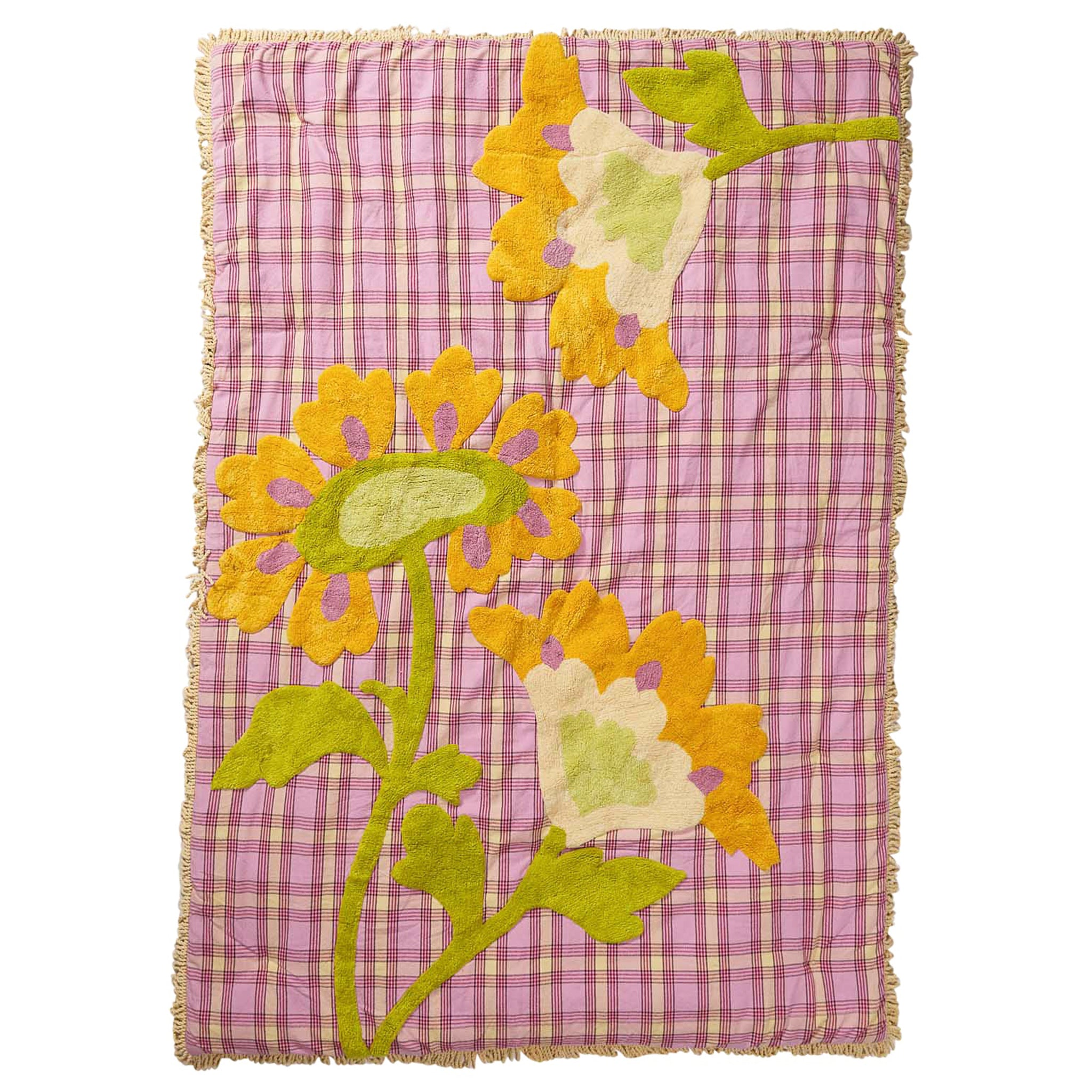 Floral-patterned quilt with yellow and green flowers on a pink checkered background