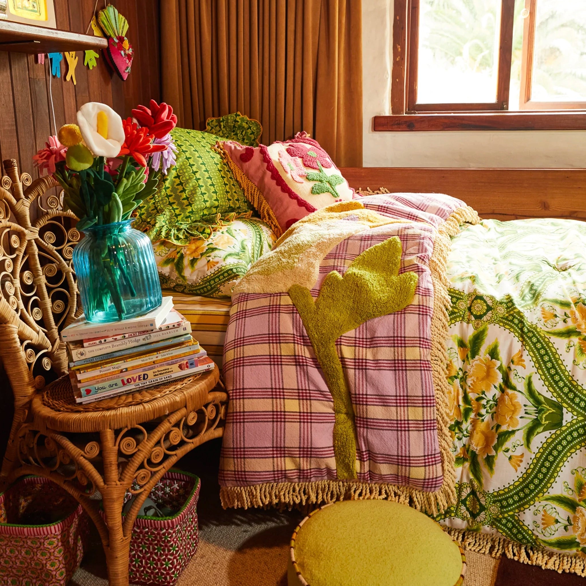 Cozy bedroom with floral arrangement, books, and colorful bedding.