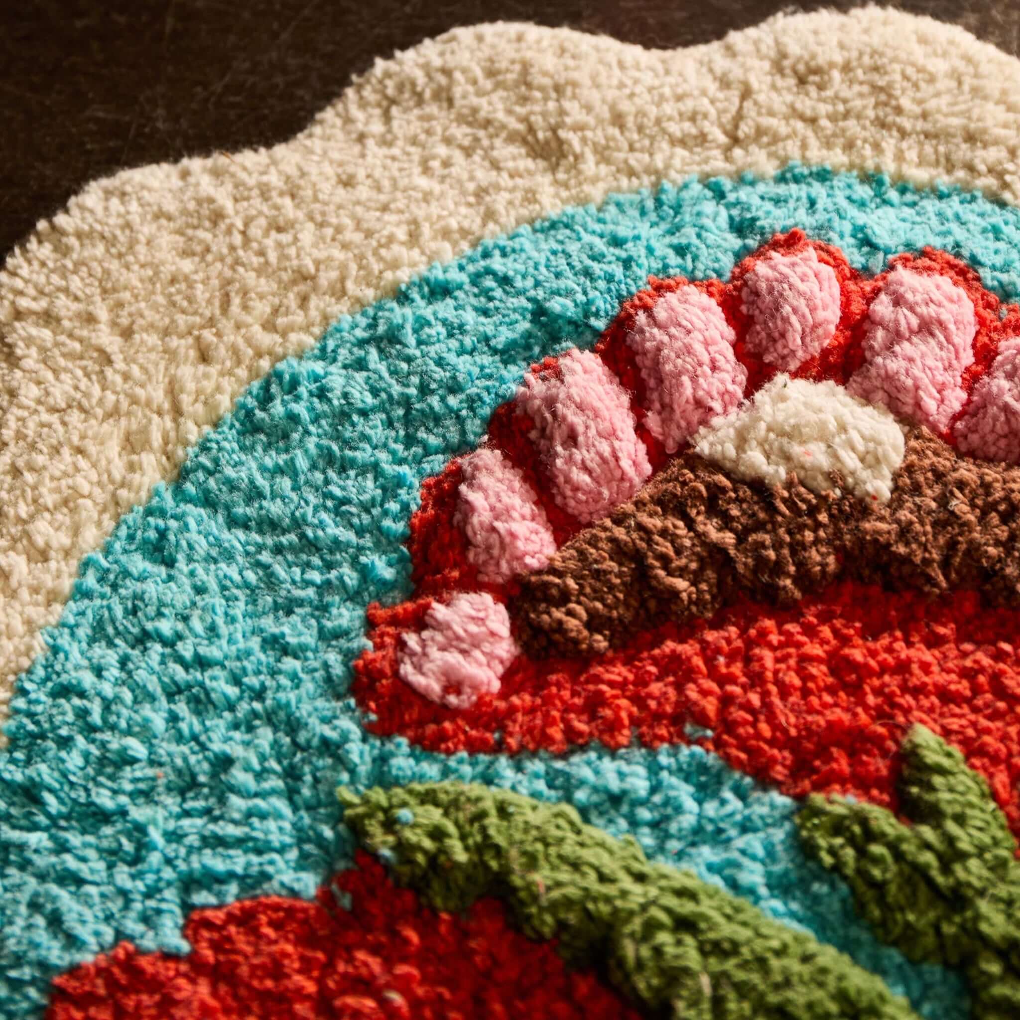 Plush detailing of the Sage x Clare Loretta Bath Mat with colorful floral design on a vibrant turquoise background.