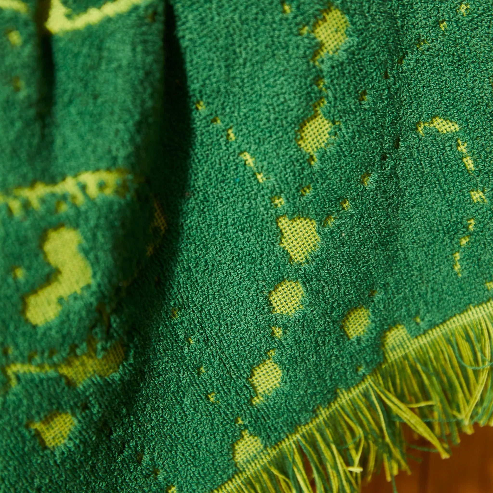 Close-up of a green fabric with yellow patterns and fringes