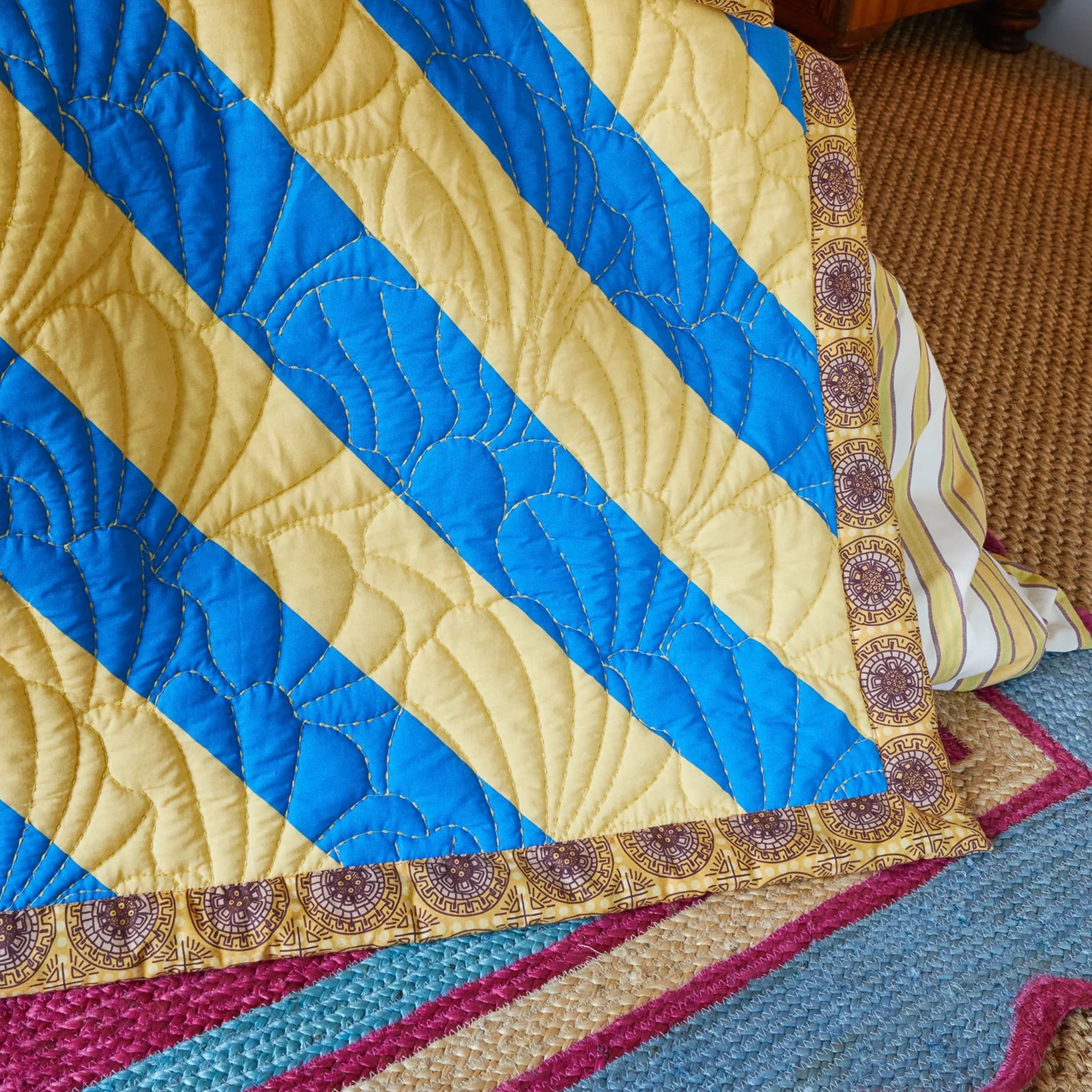 Quilt with blue and yellow diagonal stripes on a textured surface