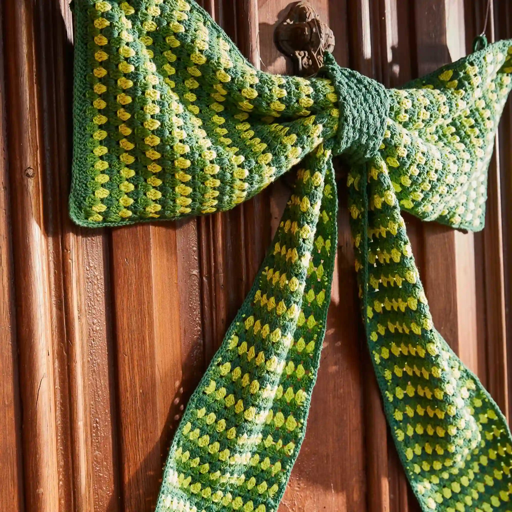 Green and yellow patterned scarf draped over a wooden surface