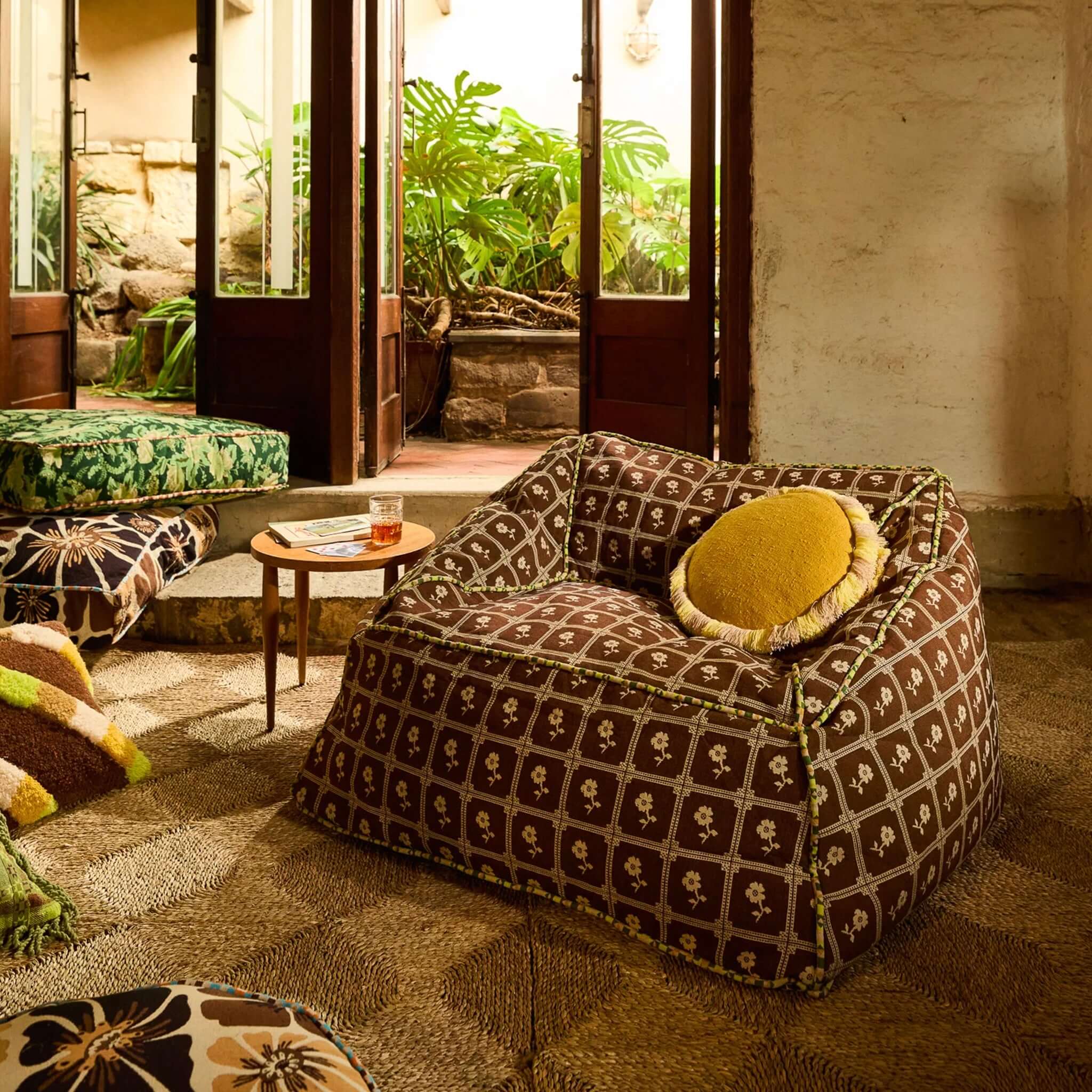 Sage x Clare Reese Round Cushion - Ochre placed on a cozy chair in a vibrant living space.
