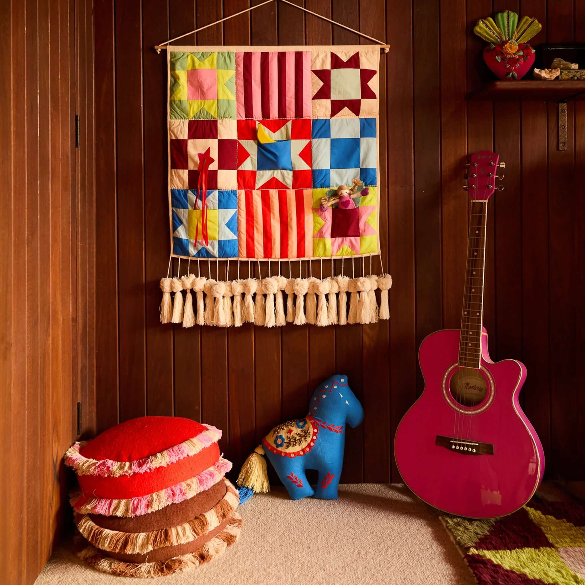 Sage x Clare Reese Round Cushion - Poppy stacked with playful decor and colorful guitar in a cozy corner.