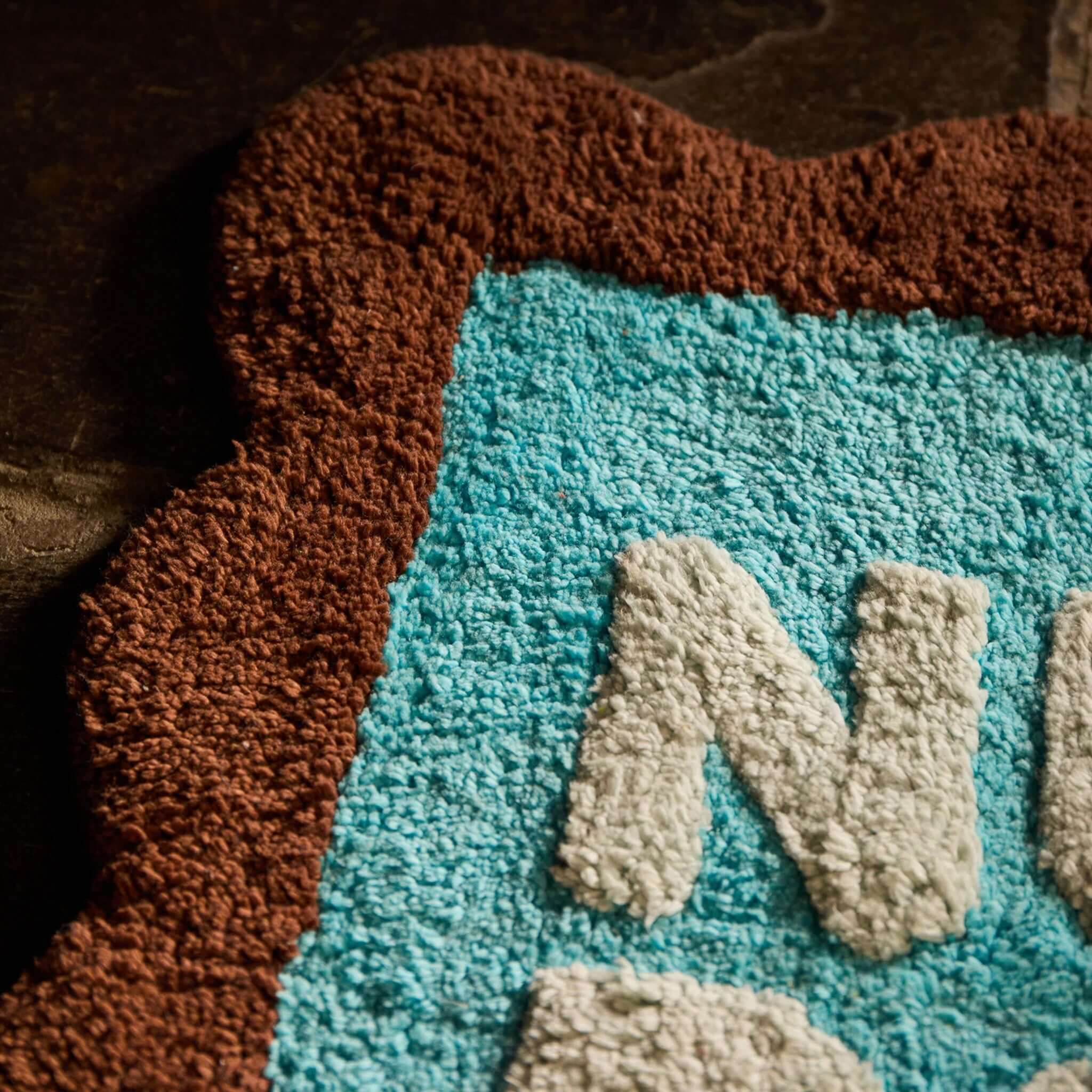 Sage x Clare Romy Nudie Bath Mat Mini - Turquoise shown with brown scalloped border and plush mint lettering.