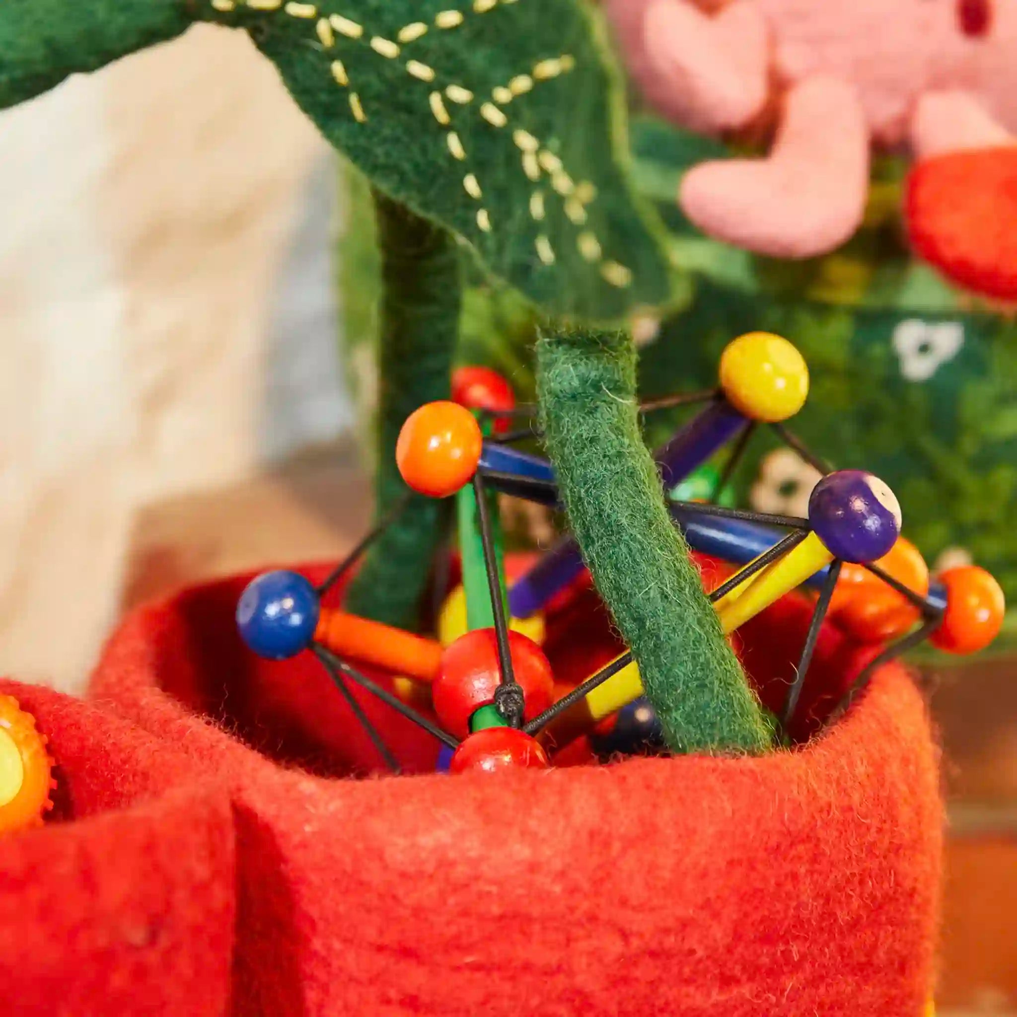 Colorful geometric toy with a green leaf-like structure inside a red container.