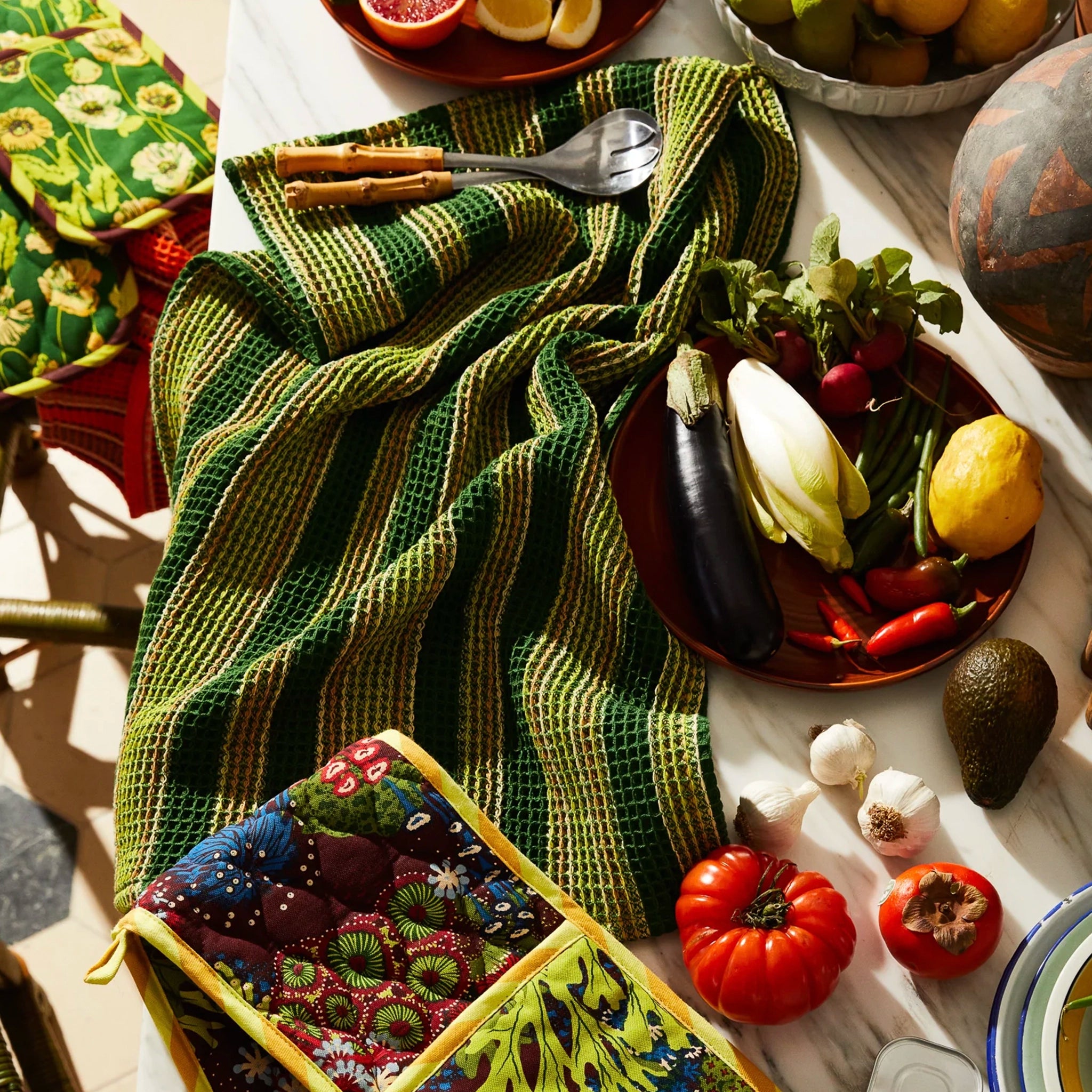 Table setting with green plaid tea towel, plates of vegetables, and decorative items.