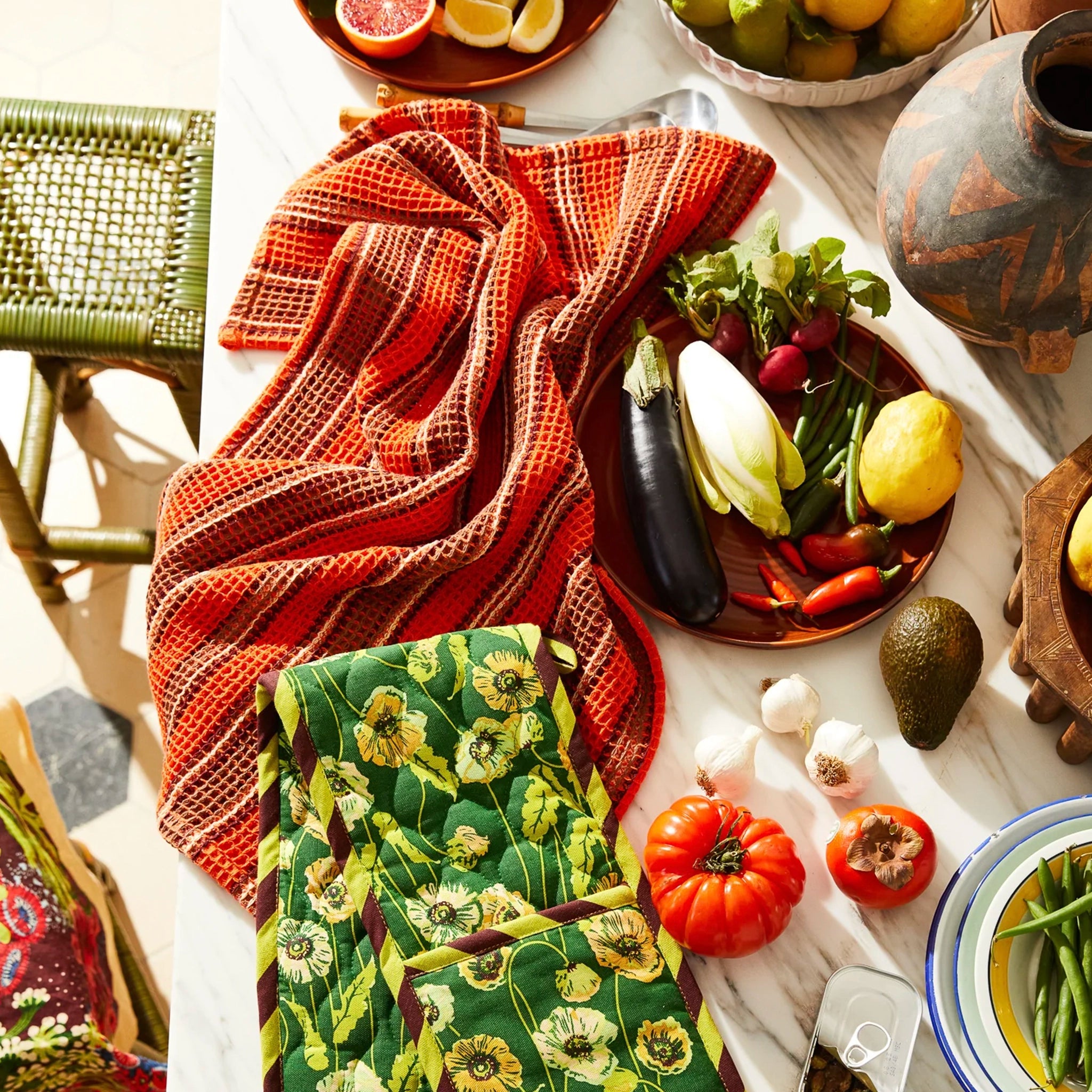 Table setting with fresh vegetables, a red tea towel on a white tablecloth.