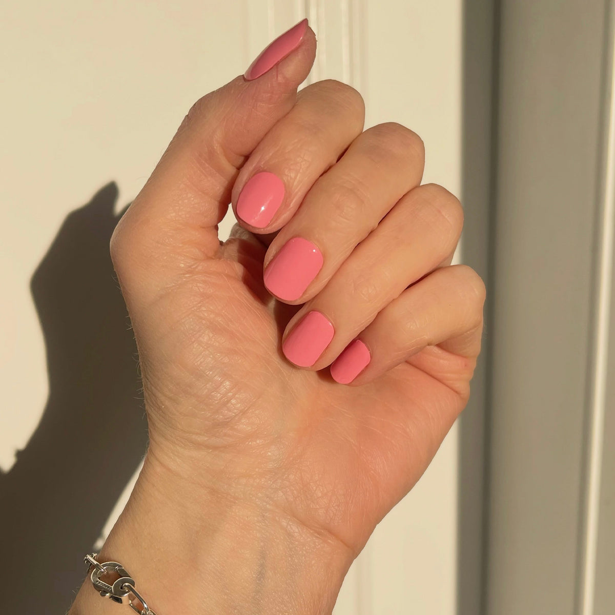 Selfie Nails Beauty Bag Nail Kit, hand with short glossy pink painted nails in sunlight