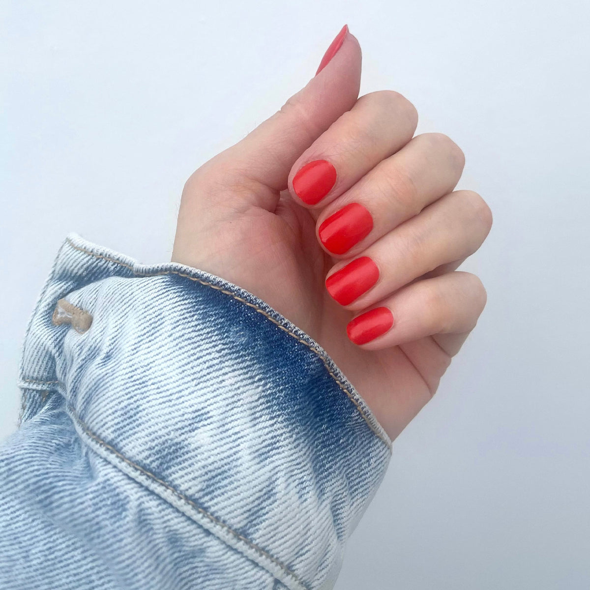 Selfie Nails Beauty Bag Nail Kit, hand with short glossy red painted nails and denim sleeve