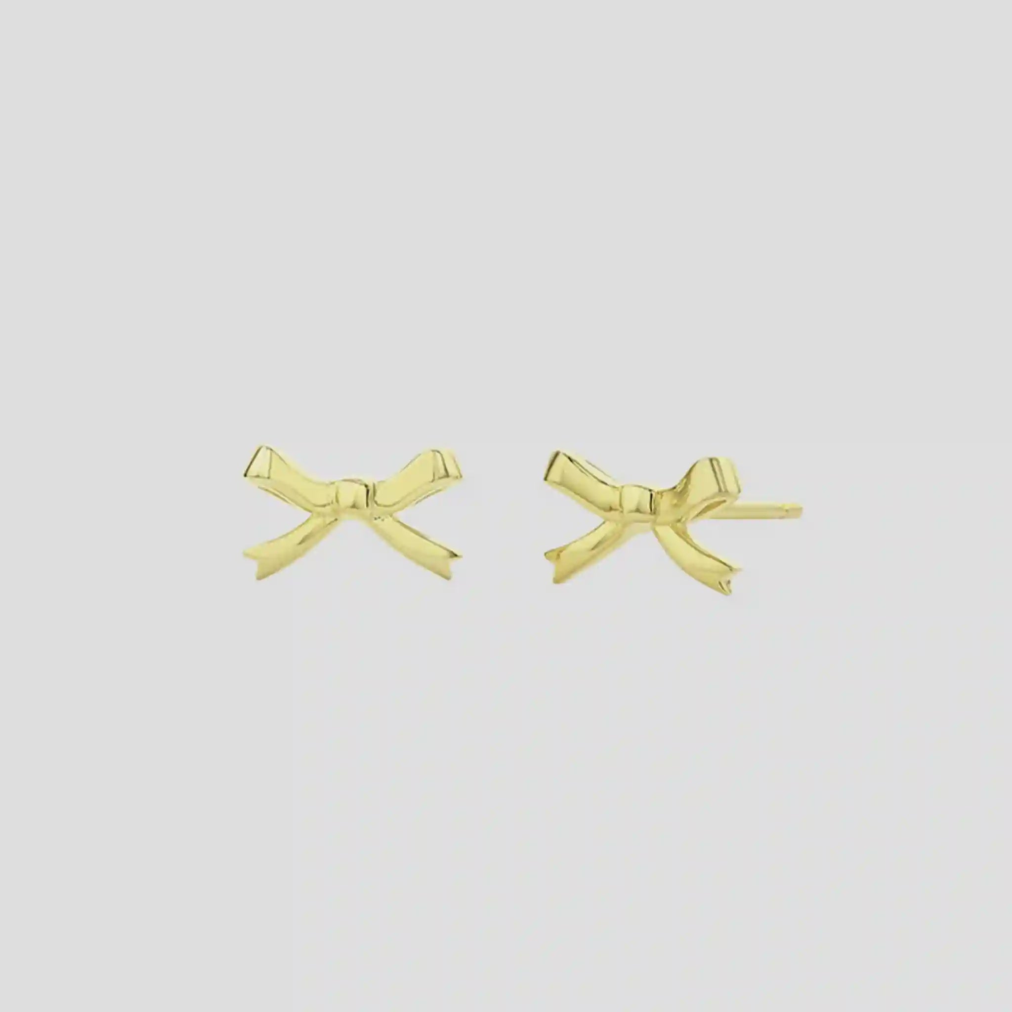 Gold bow-shaped earrings on a light gray background