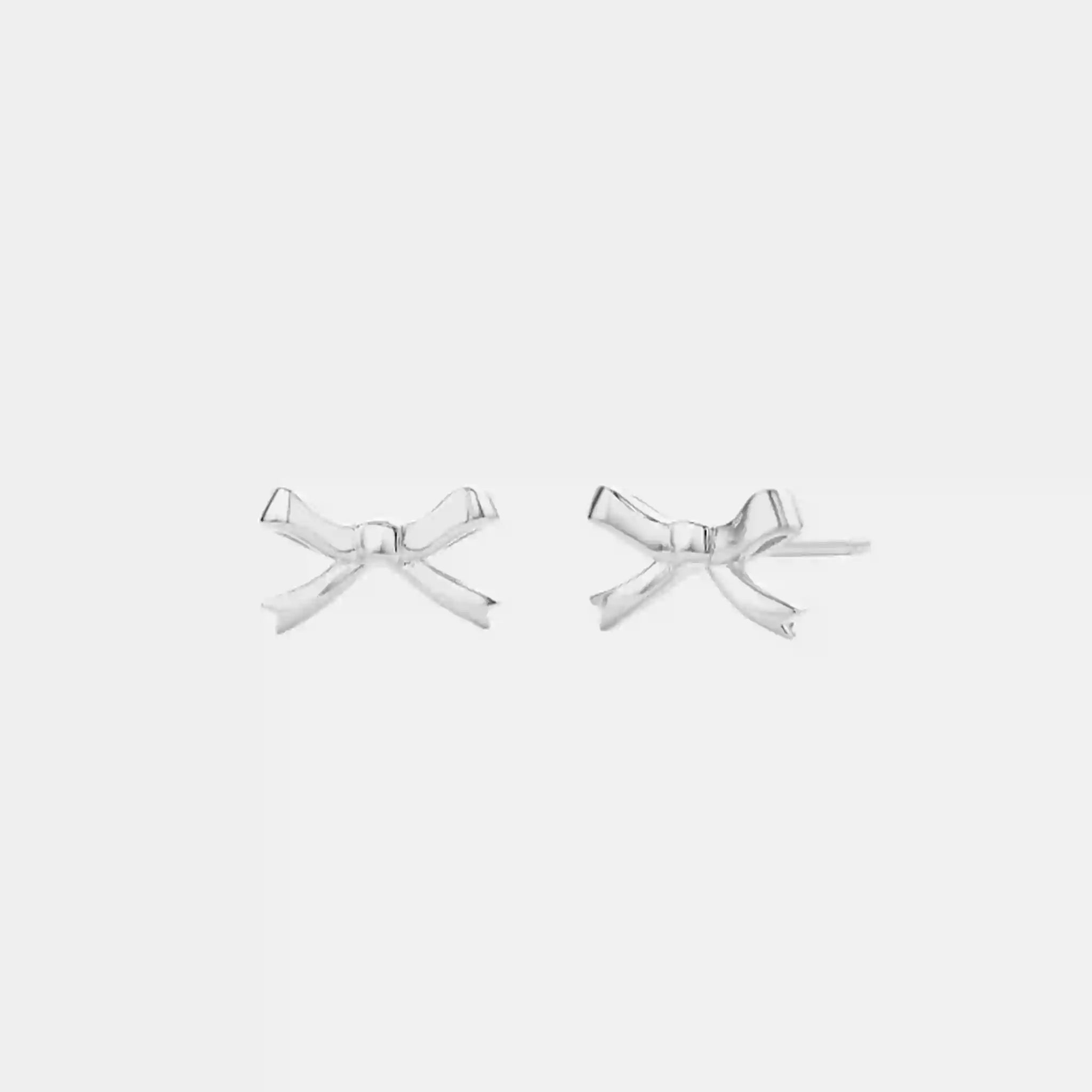 Silver bow-shaped earrings on a white background