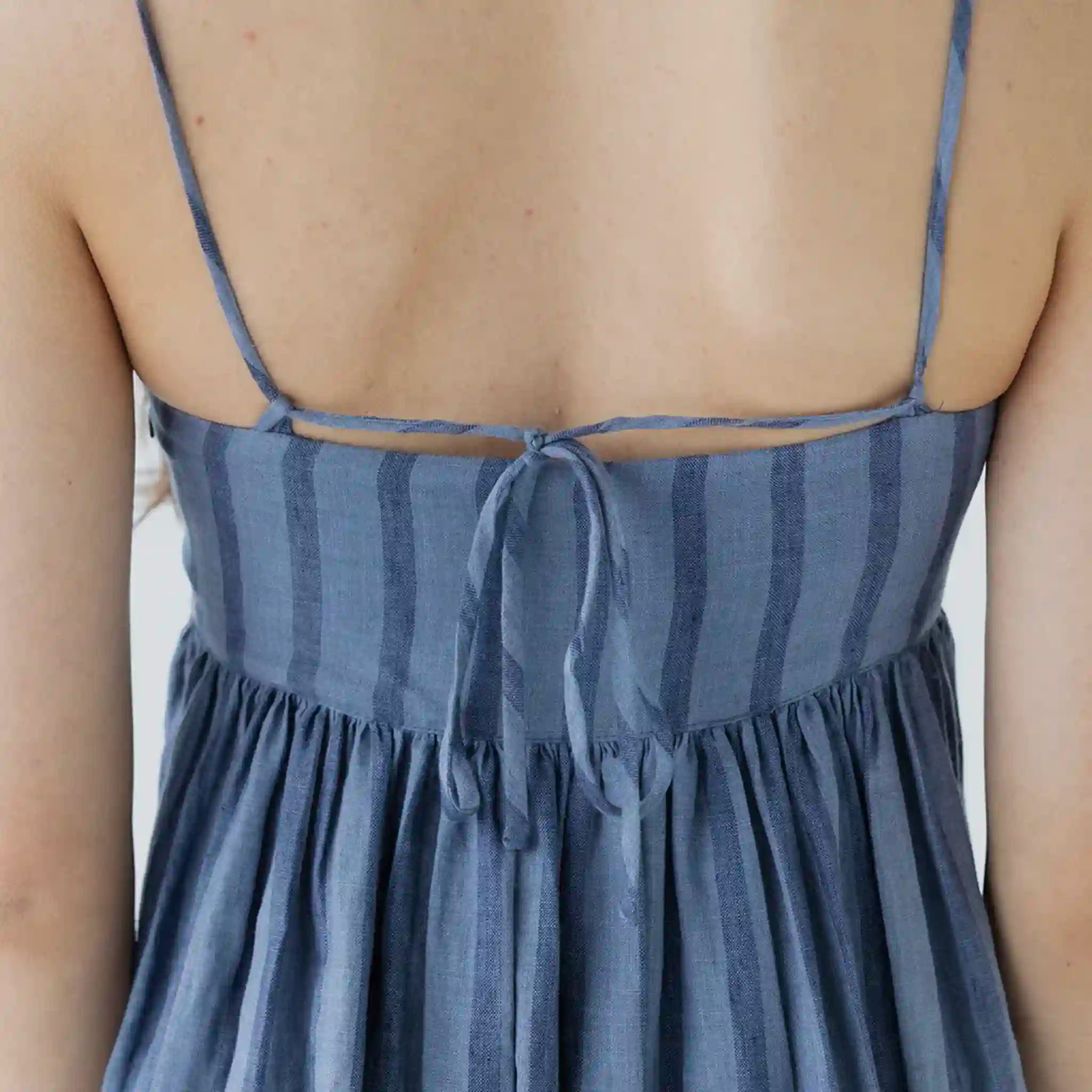 Blue striped dress with thin straps on a neutral background