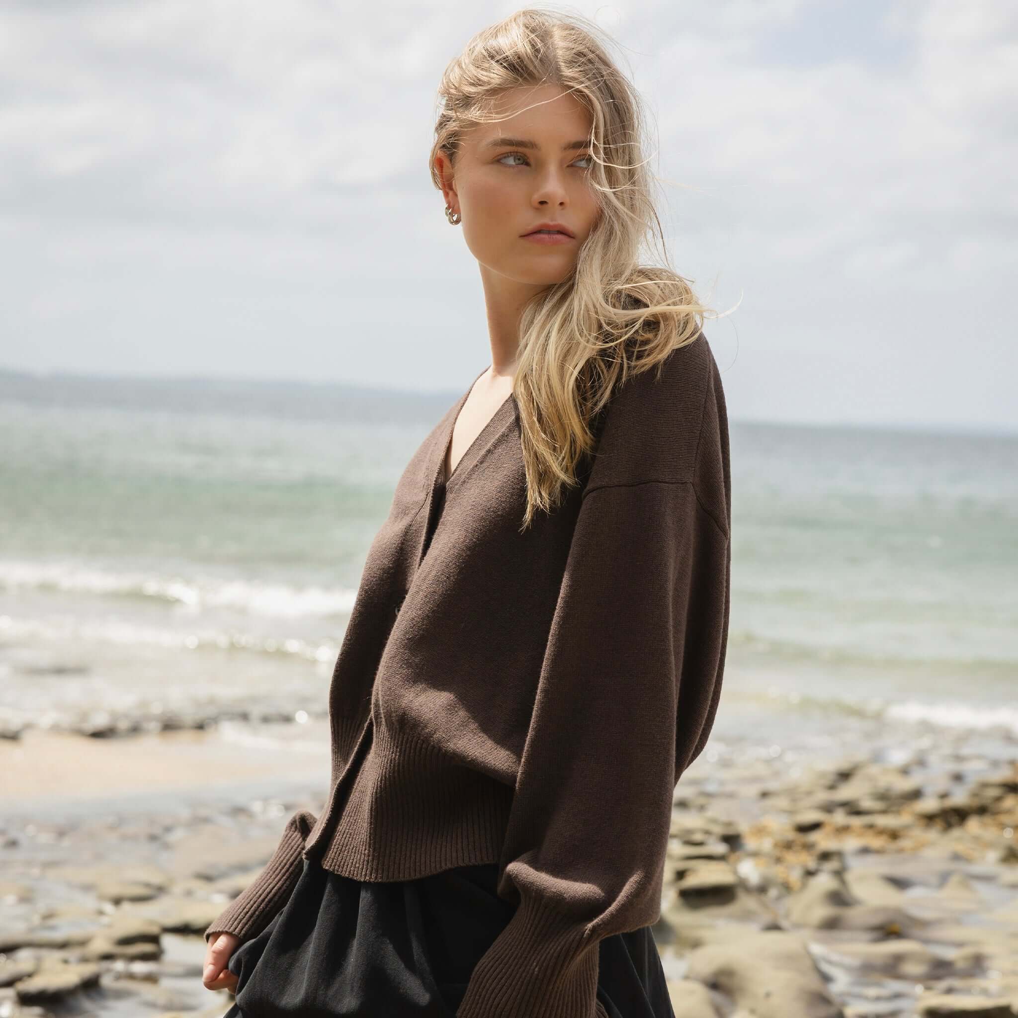Alt Tag: Sophie Love Me Cotton & Cashmere Cardigan - Cocoa worn by model on beach, relaxed oversized V-neck cardigan with dropped shoulders