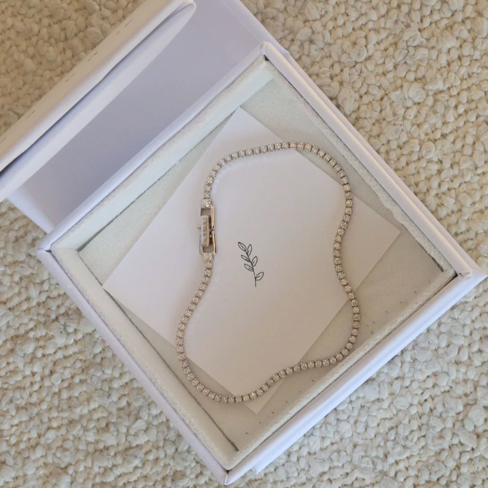 Silver bracelet in a jewelry box on a textured surface
