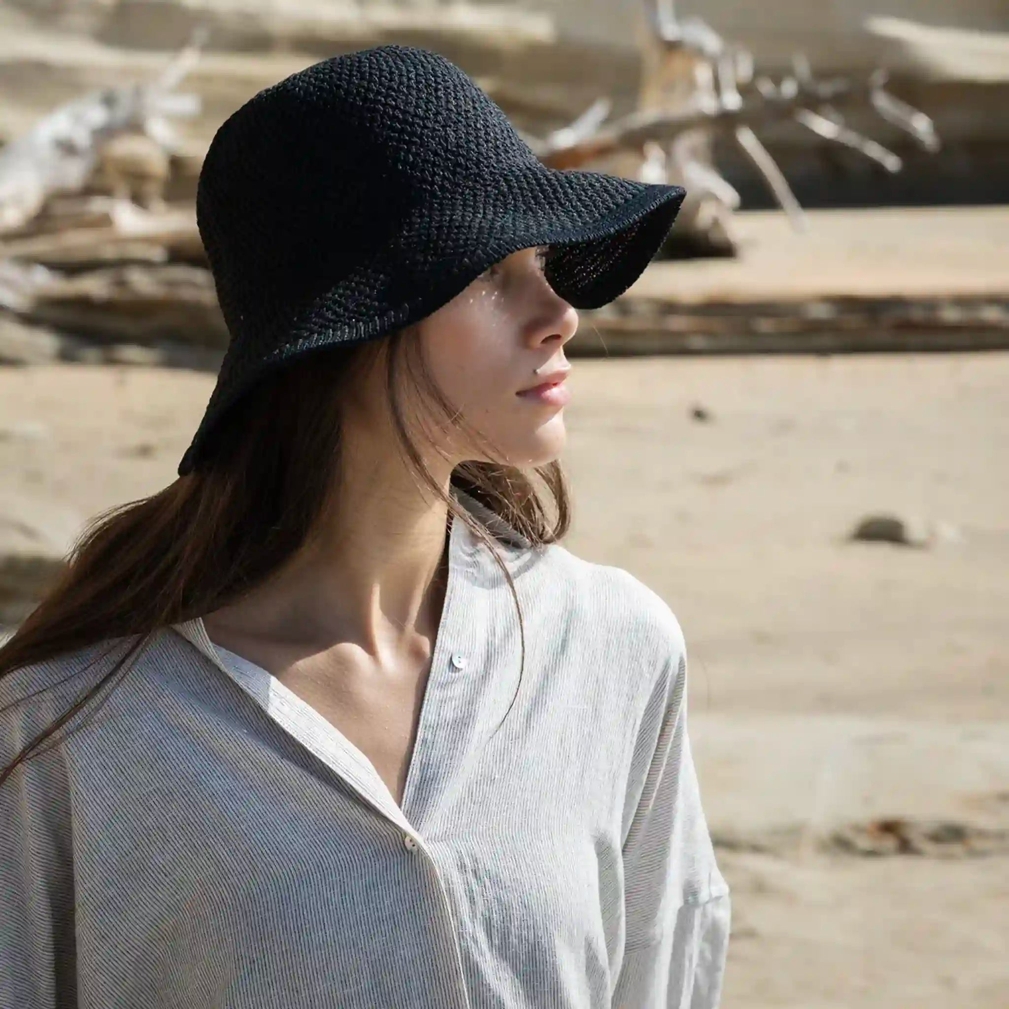 Woman wearing a black straw hat in a desert setting