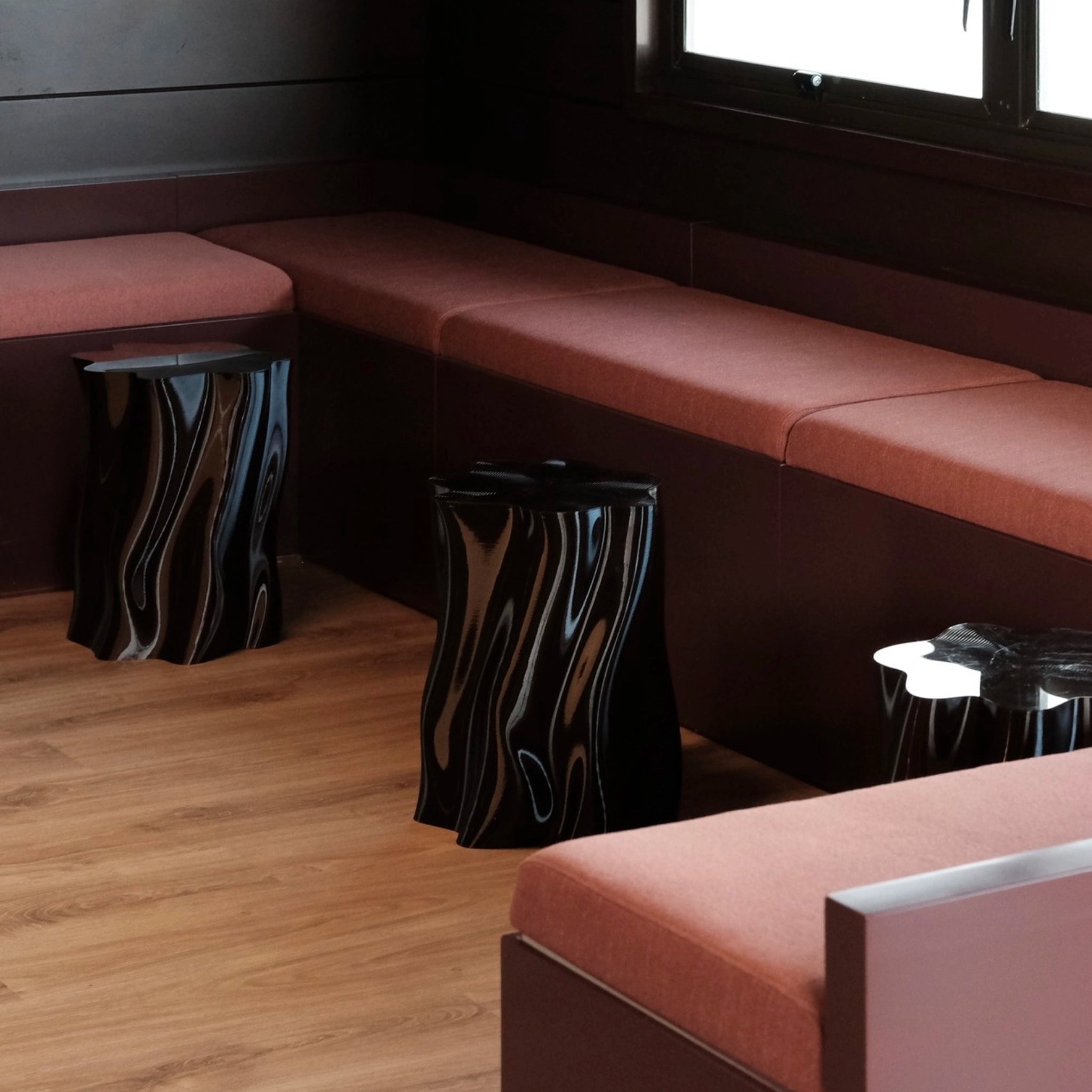 Sectional brown sofa with patterned stools on a wooden floor.