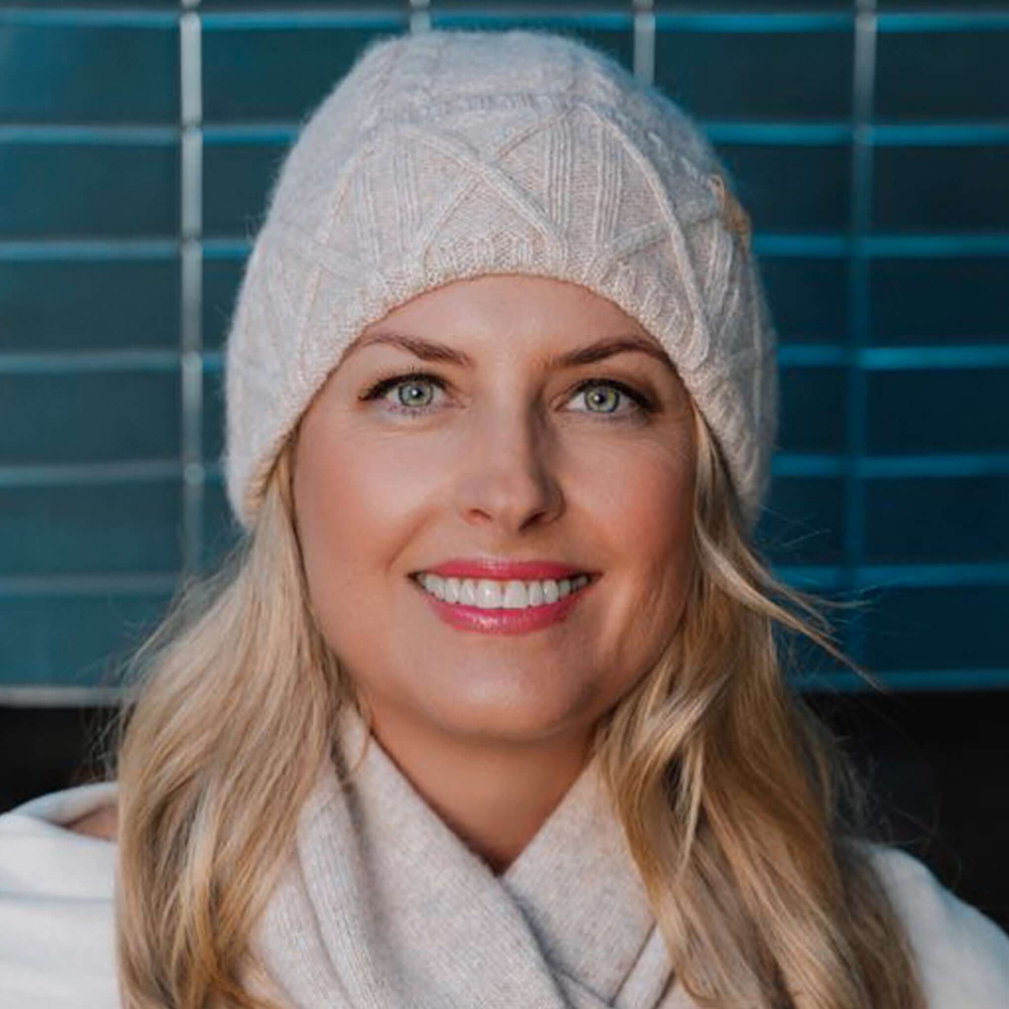 Sundaise Hotham Cashmere & Wool Beanie - Light Oat worn by a smiling woman, perfect for winter warmth and style.