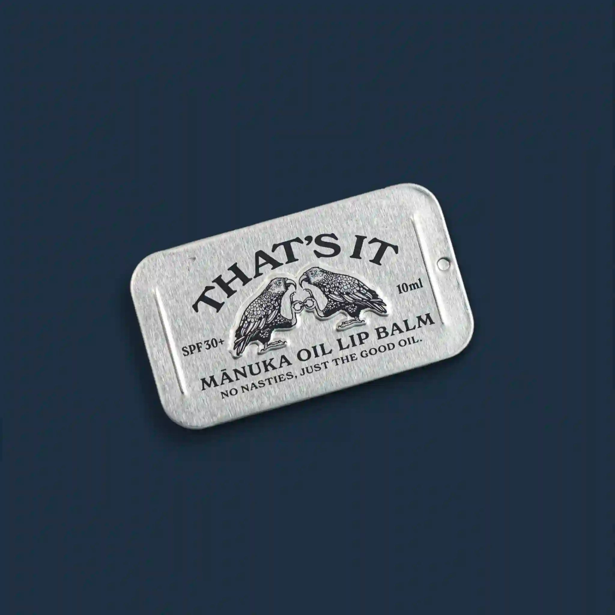 Manuka oil lip balm packaging with branding on a dark blue background