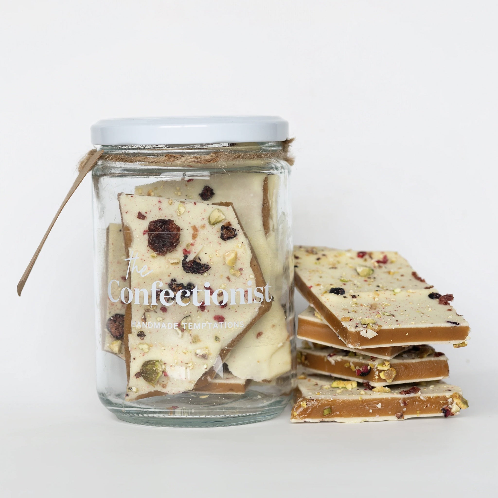 Glass jar of confectionery with a stack of pieces on a white background, branded 'The Confectionist'.