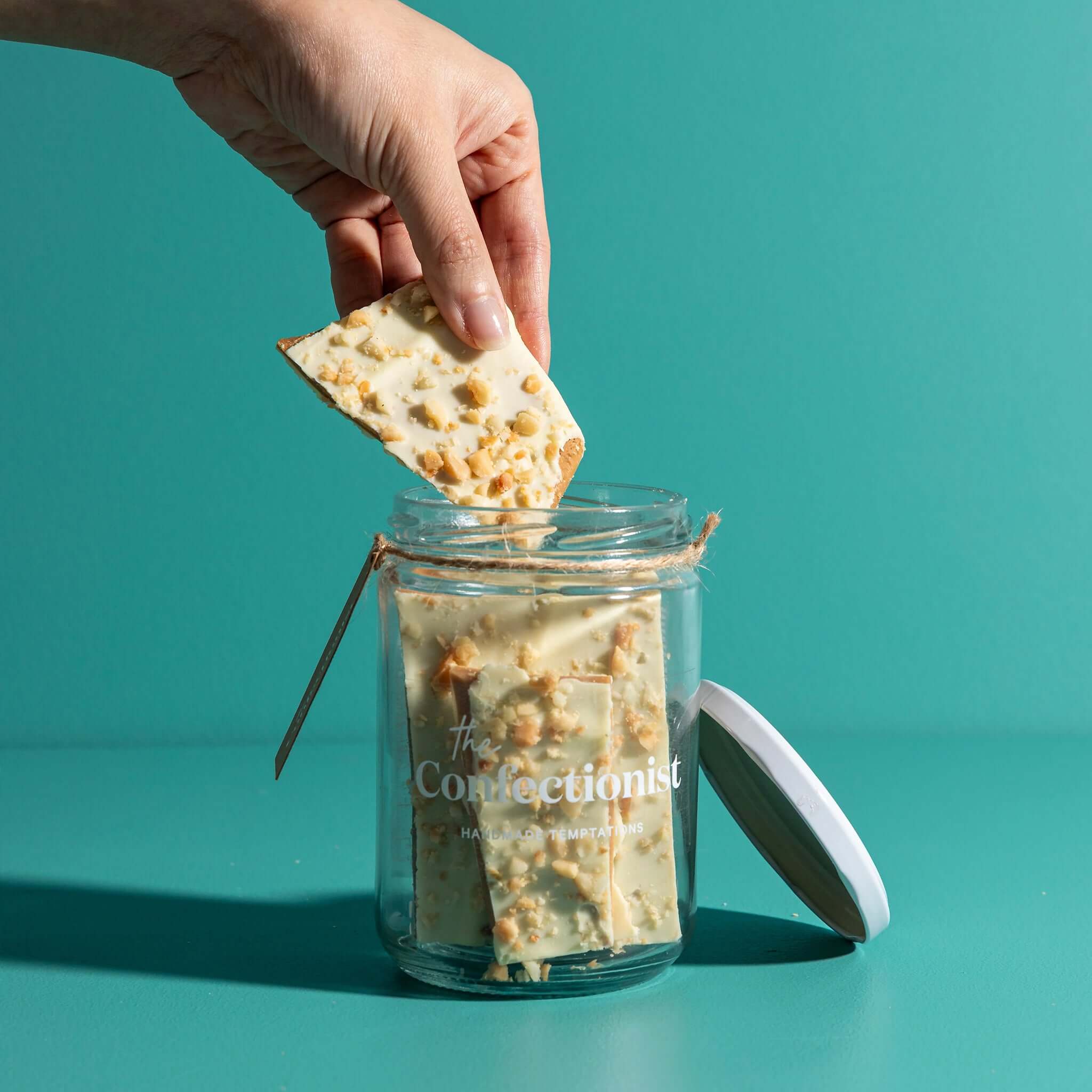 The Confectionist Limited Edition White Chocolate, Macadamia & Lemon Toffee - Large in a jar with toffee being served.