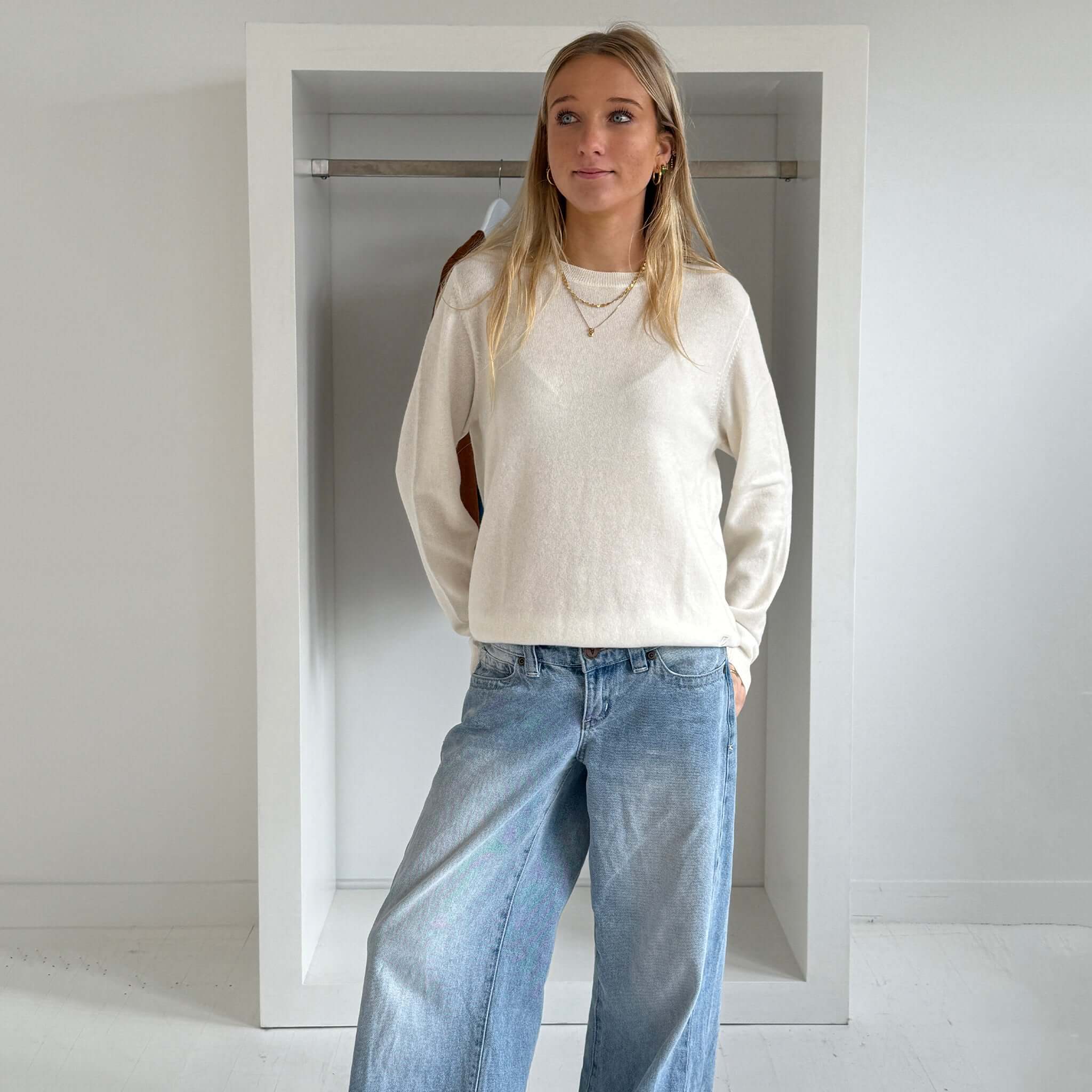 The Uniform Cashmere Crew Neck Sweater - Milk worn by a model, showcasing a relaxed fit and sophisticated design.