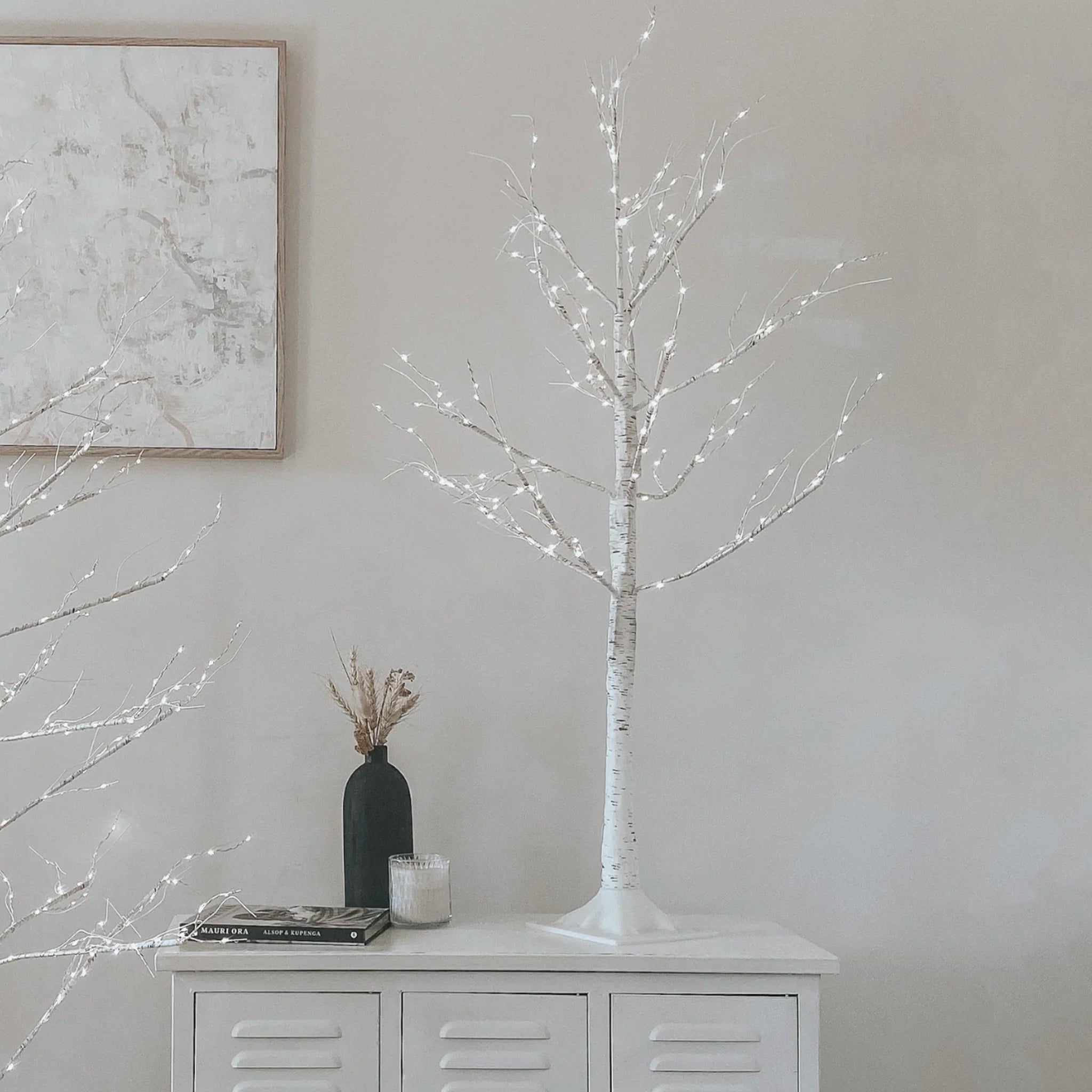 Decorative LED tree on a white cabinet with a neutral wall background