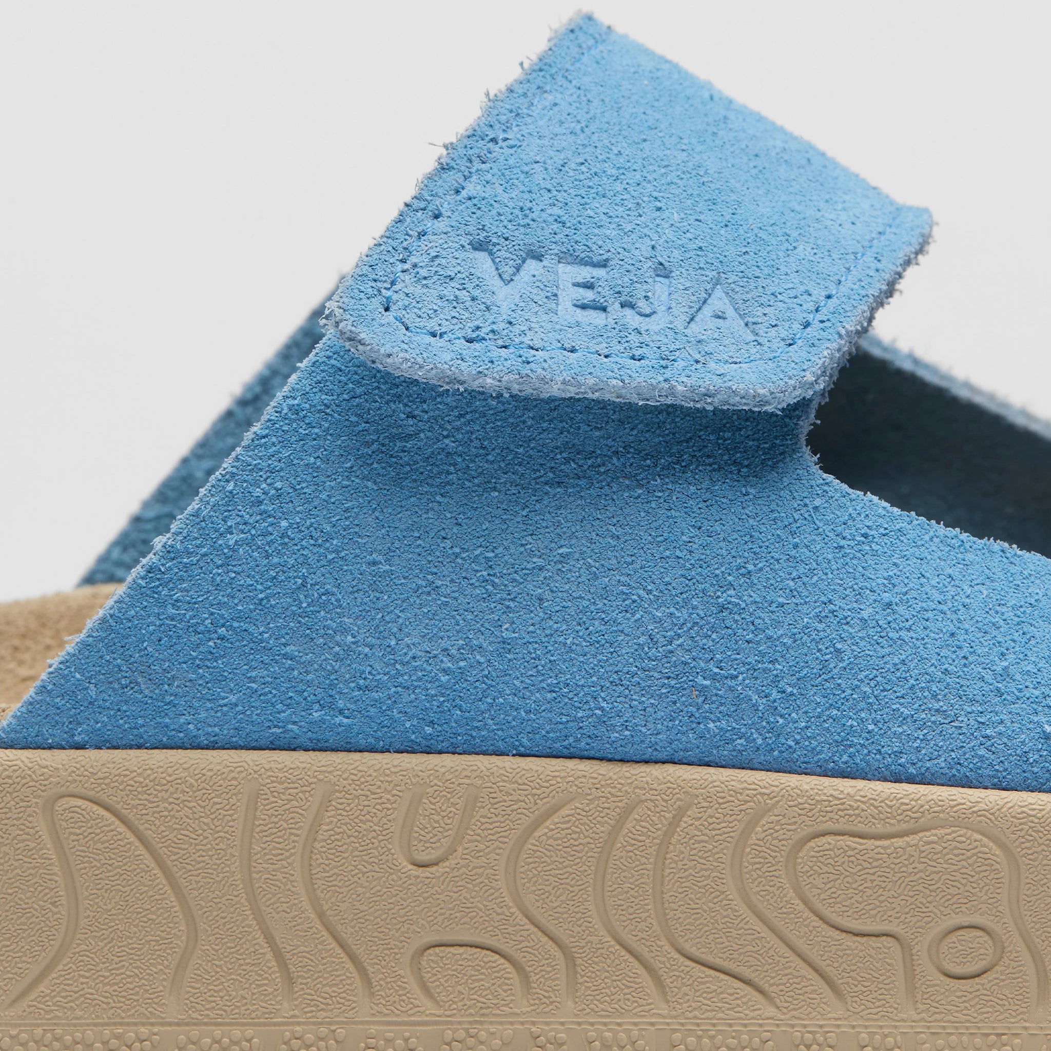 Close-up of blue sandals with a visible brand logo on a light gray background